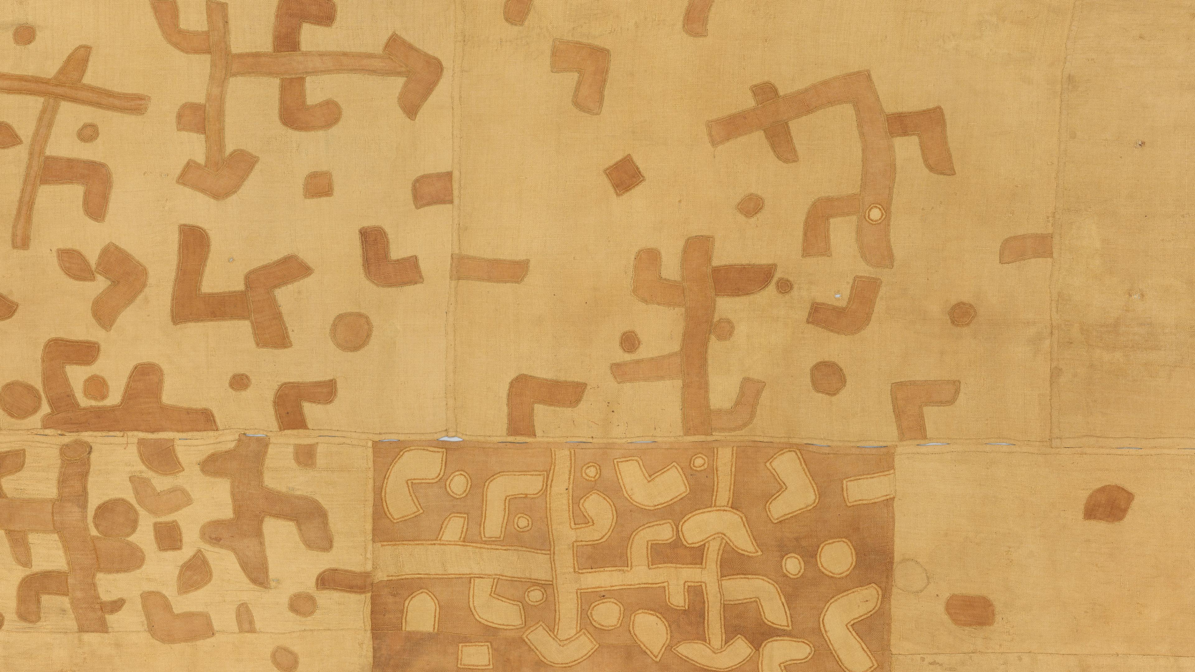 Detail of a fabric with brown geometric symbols that fade and grow sparser across its length.