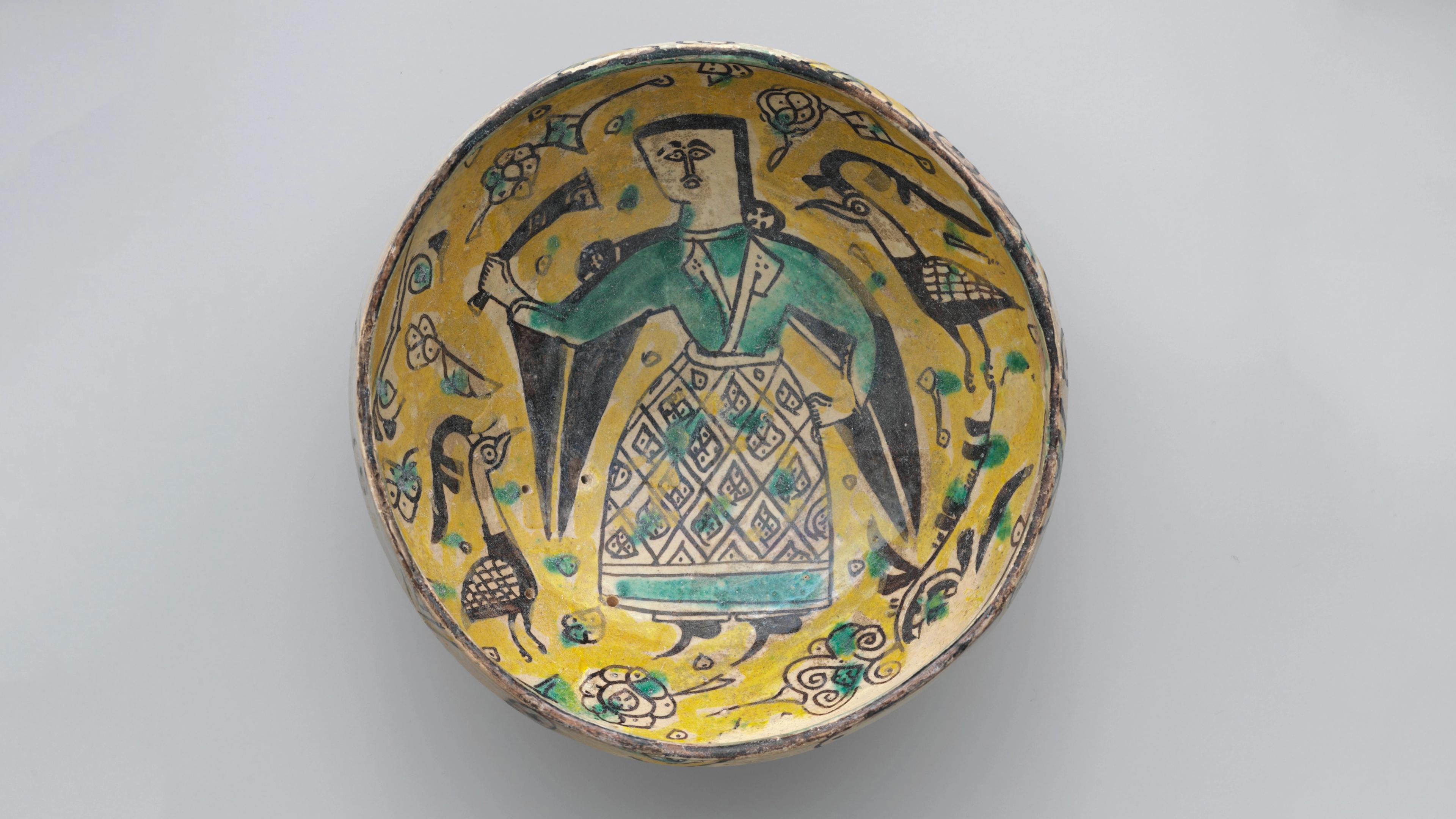 Yellow bowl with a central, angular figure in a green patterned dress surrounded by birds.