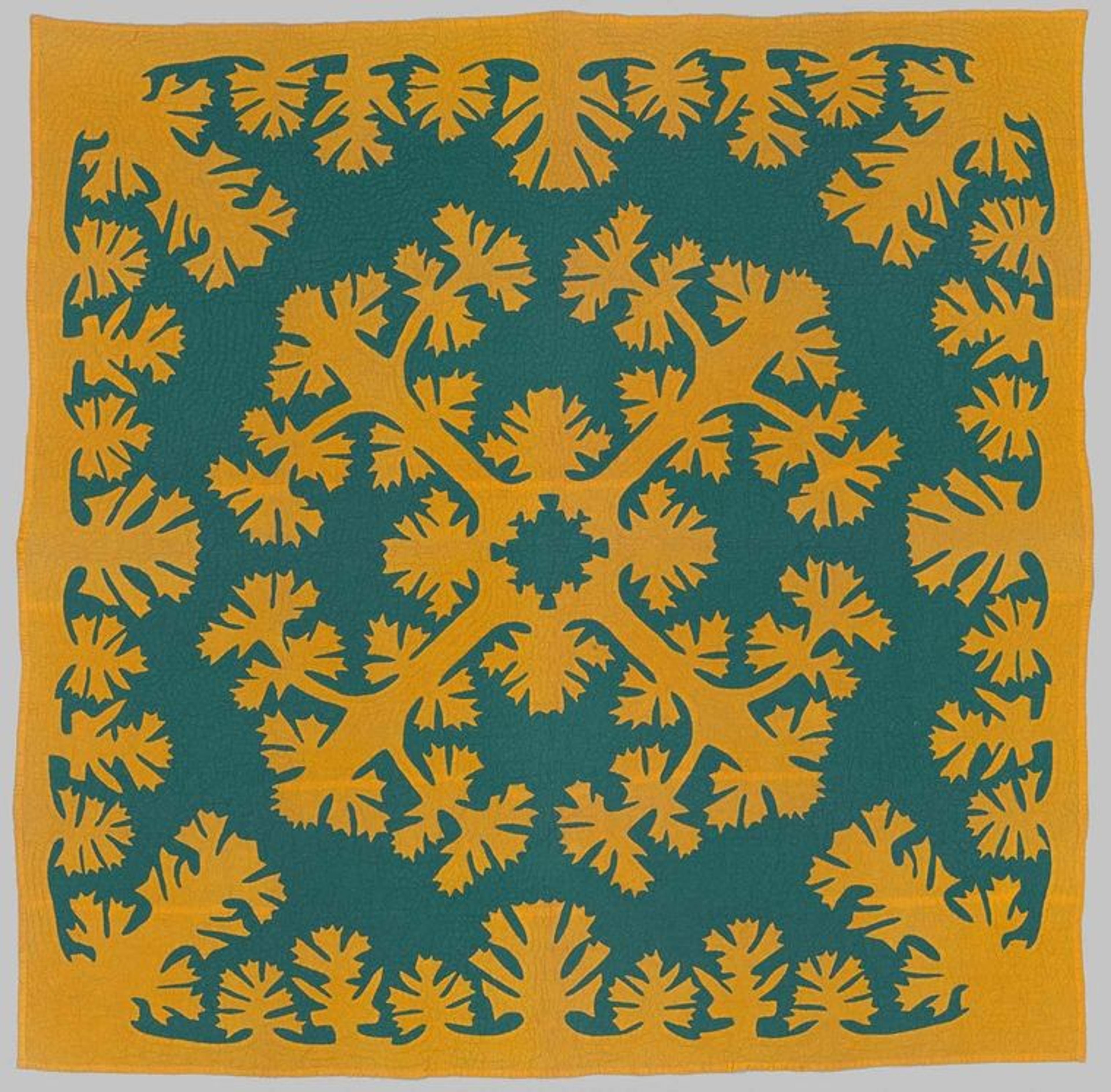 A teal quilt with yellow fringe and a symmetrical yellow design in its center. Both the center and edge designs feature complex, ornate, flower blossom-like patterns that extend identically into all four corners of the quilt.