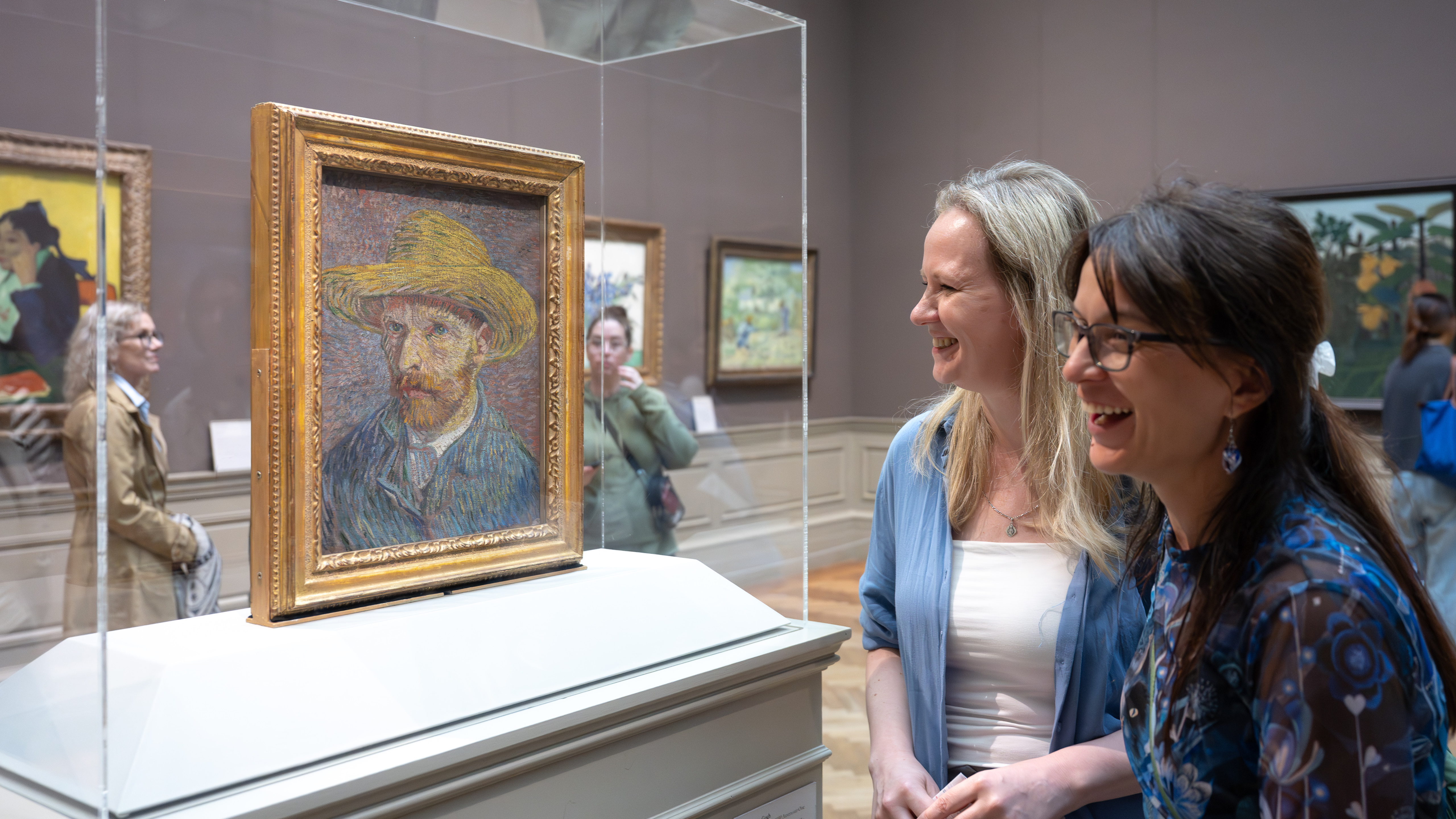 A group of people in front of Van Gogh's Self-Portrait with a Straw Hat (obverse: The Potato Peeler)