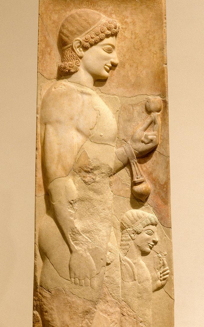 Carving on a marble stele of a youth and his little sister. The young man is holding a pomegranate and an oil flask, while the girl holds a flower.