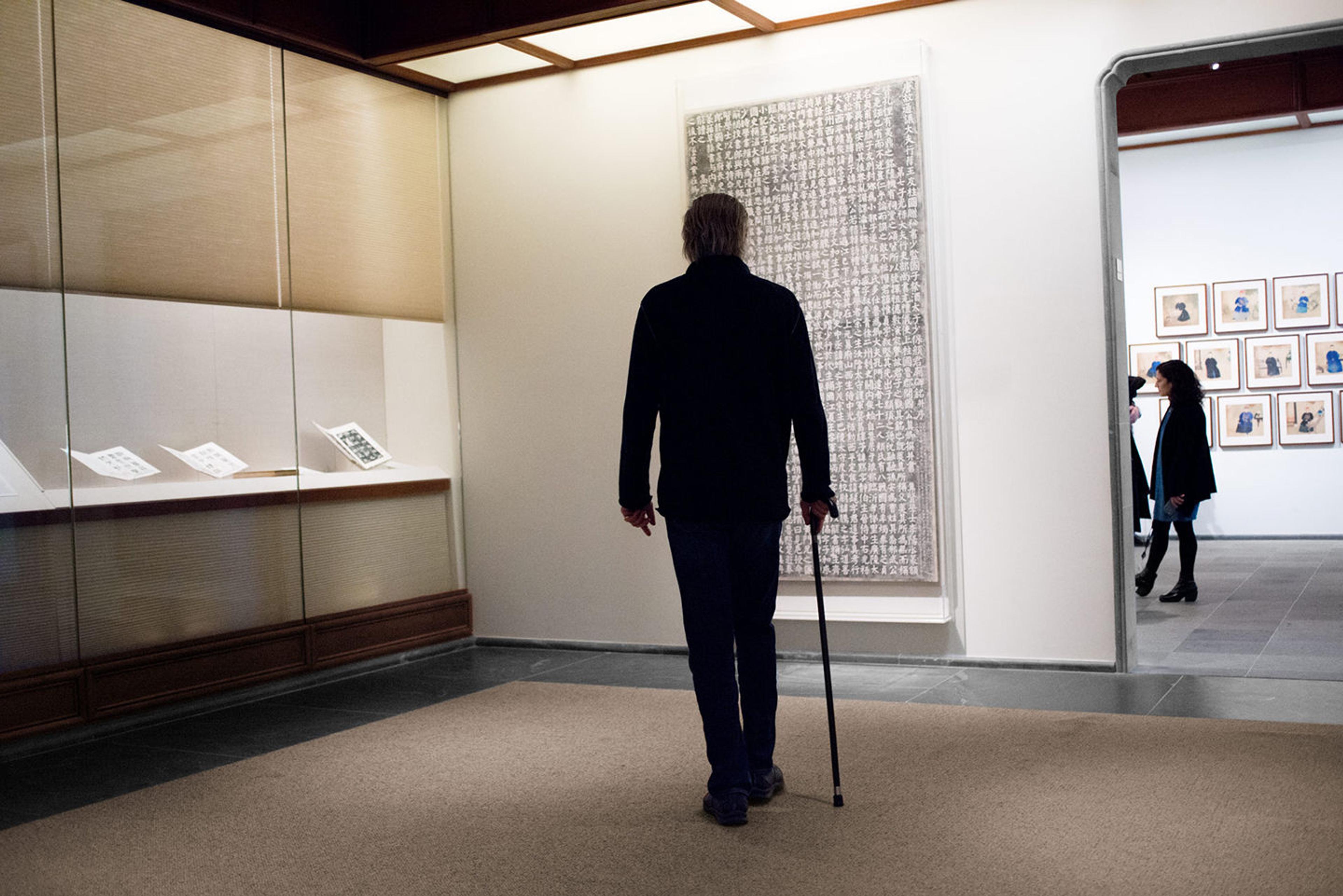 The artist James Nares contemplates a display of Chinese calligraphy in the Department of Asian Art's galleries