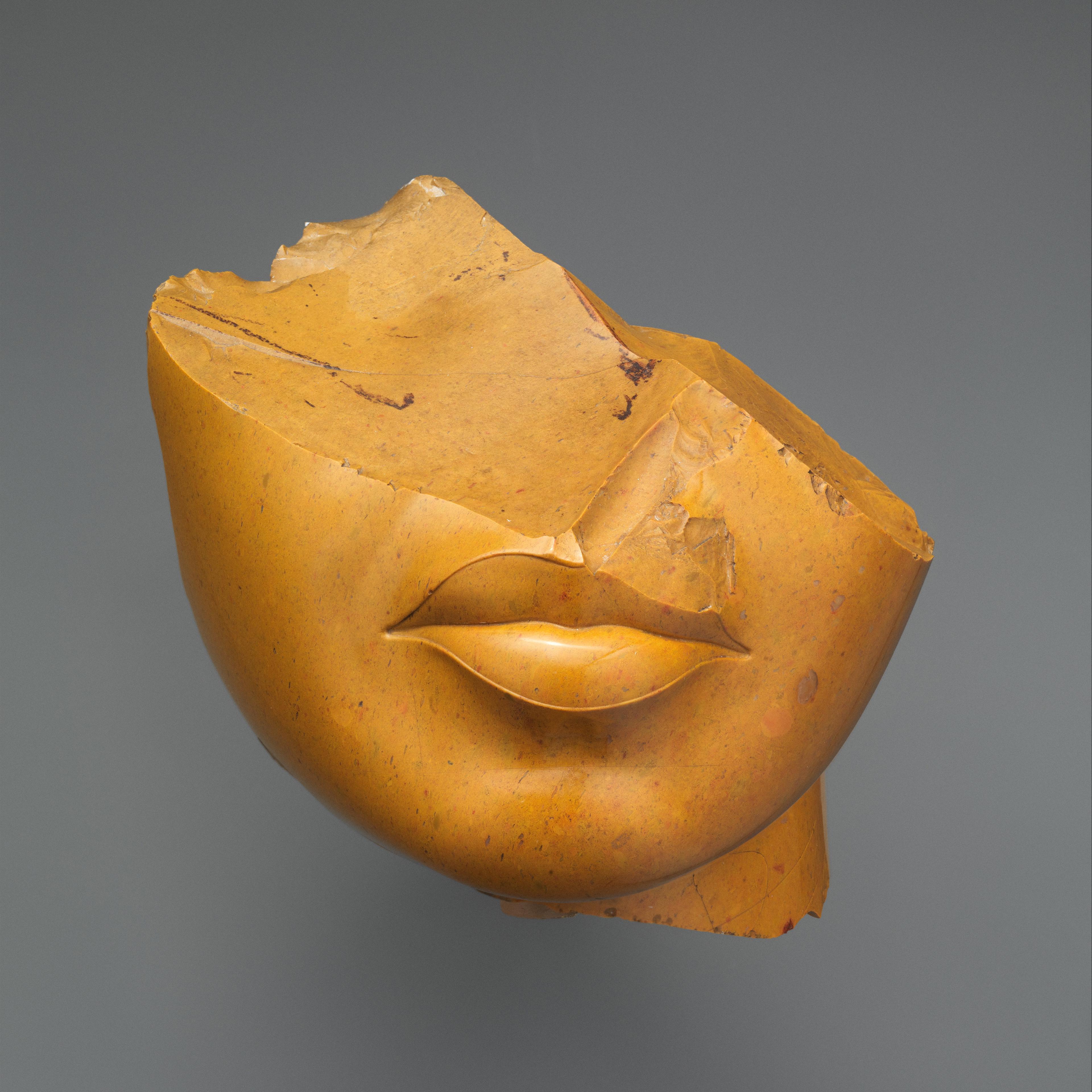 Fragment of a Queen's Face made out of yellow jasper. Only the bottom half of her face, her lips and chin are discernible.