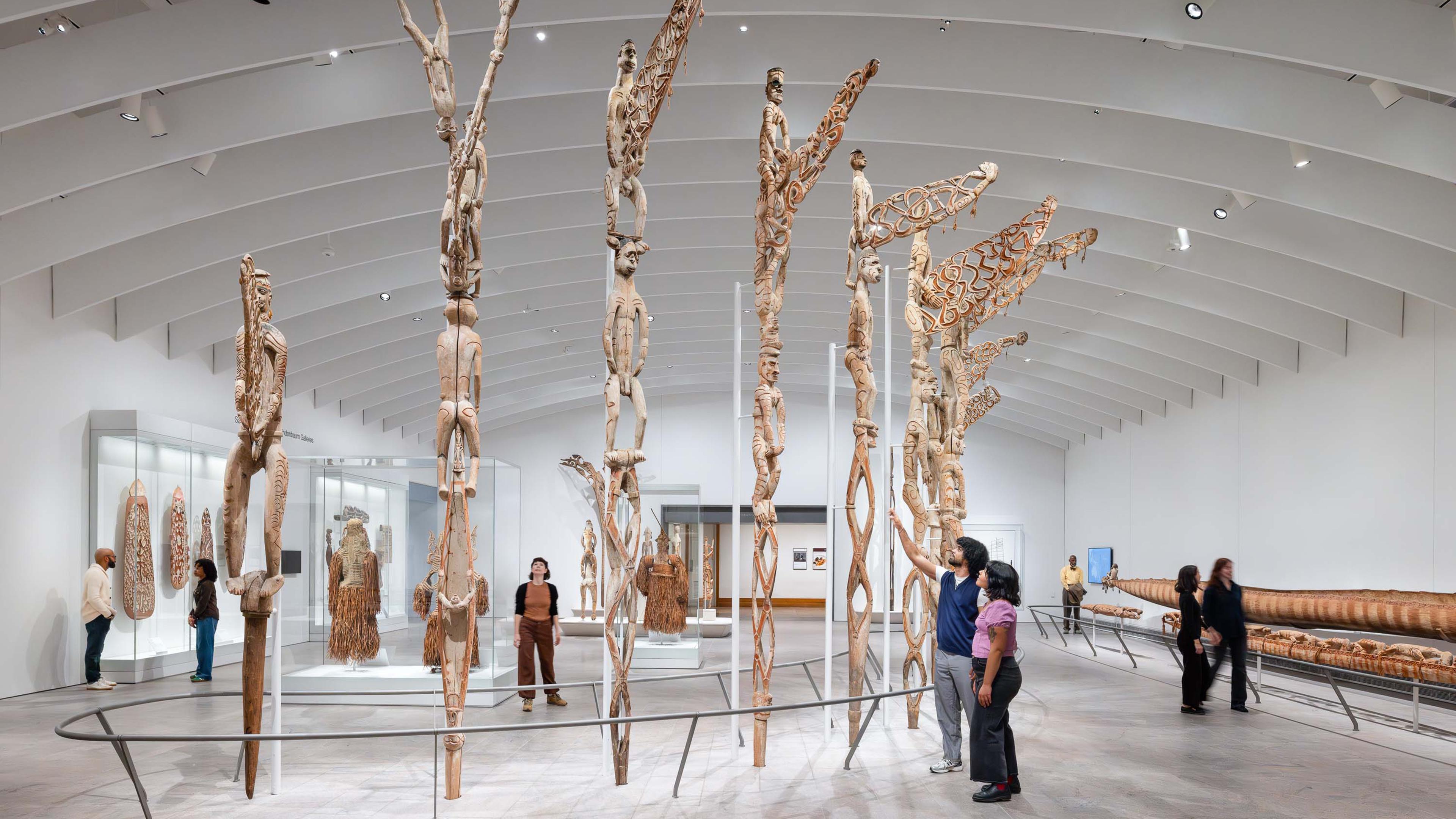 Visitors looking at the Bisj poles in the new Oceania galleries in the Michael C. Rockefeller Wing