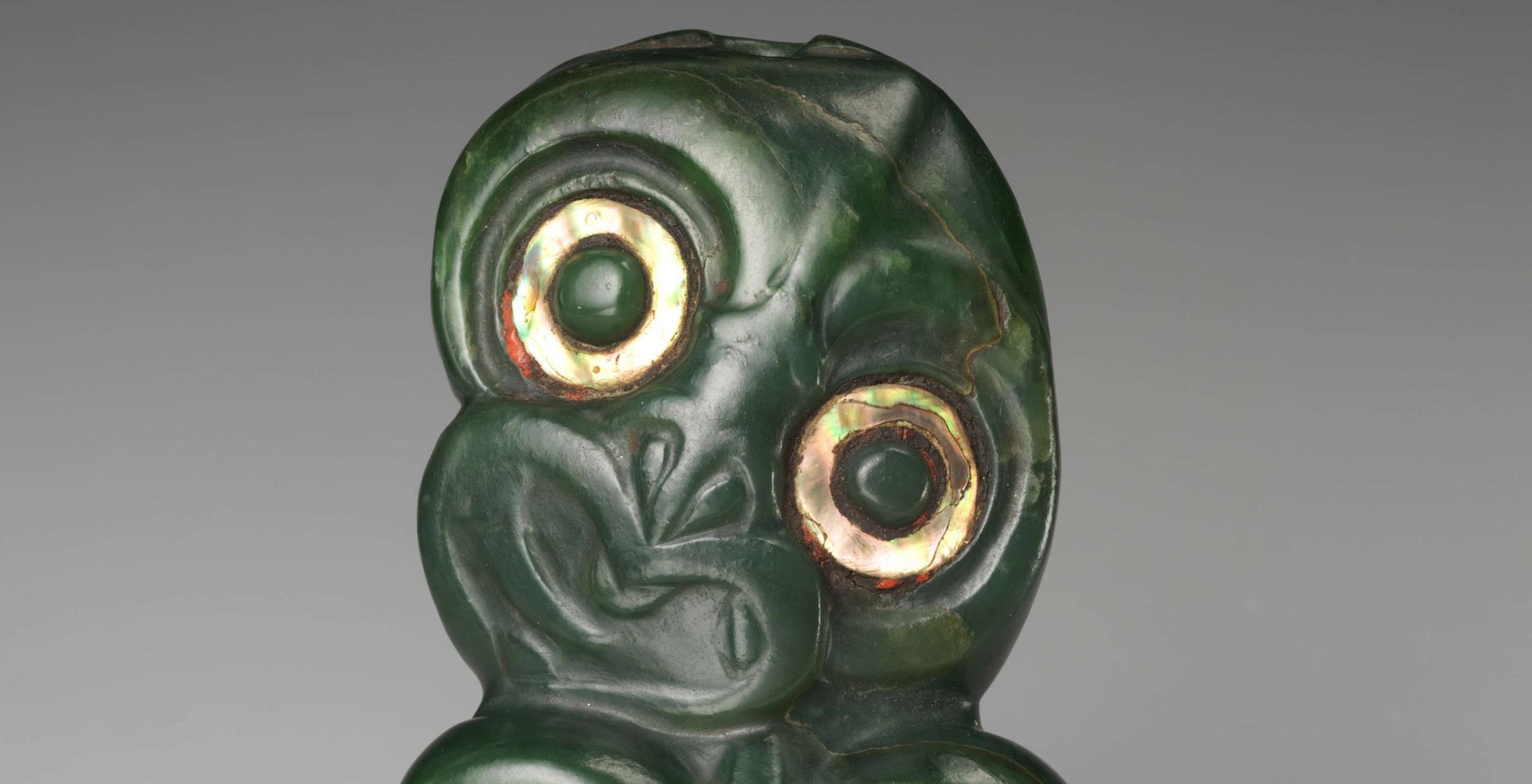 Maori hei tiki, or greenstone pendant, carved with large eyes and abstracted human facial features, embryonic quality