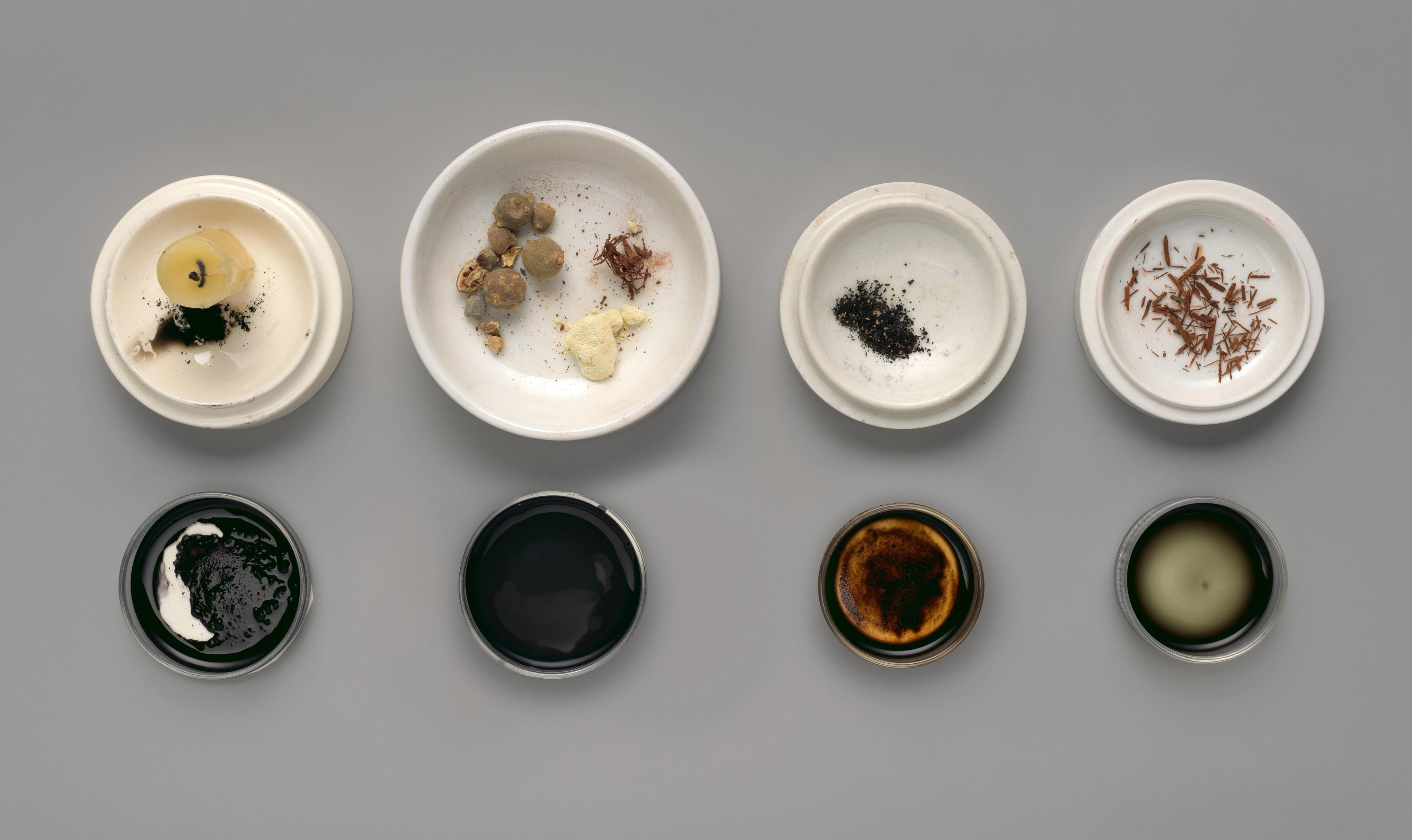 A neat arrangement of liquid inks in open containers below plates of the materials they are ground from.