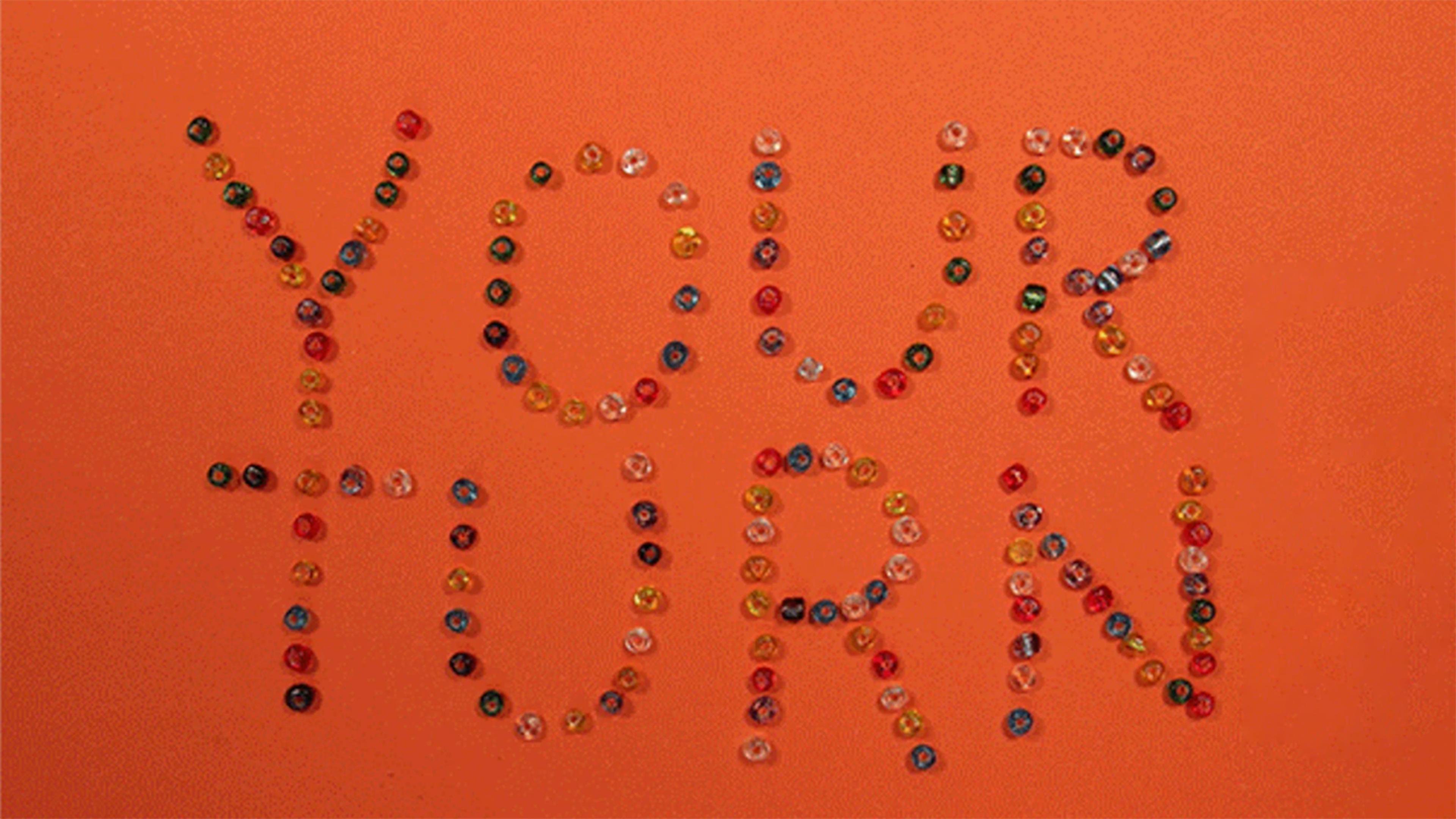 Beads spelling out "YOUR TURN" against an orange background.