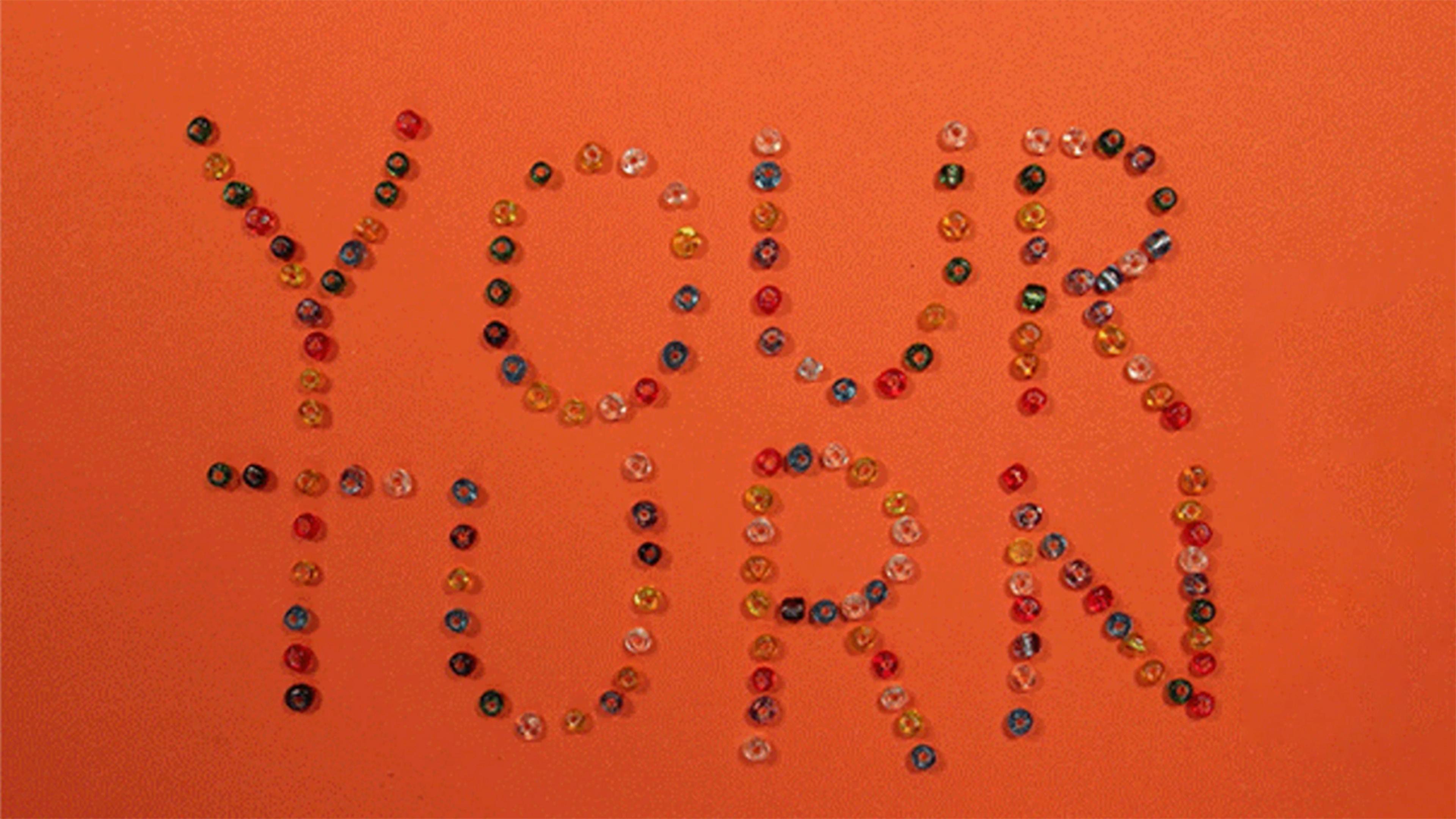 Beads spelling out "YOUR TURN" against an orange background.