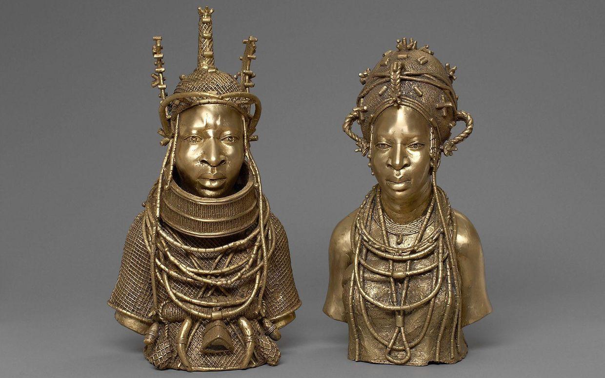 Two intricately detailed brass busts depicting regal African figures adorned with elaborate headdresses, jewelry, and traditional attire.