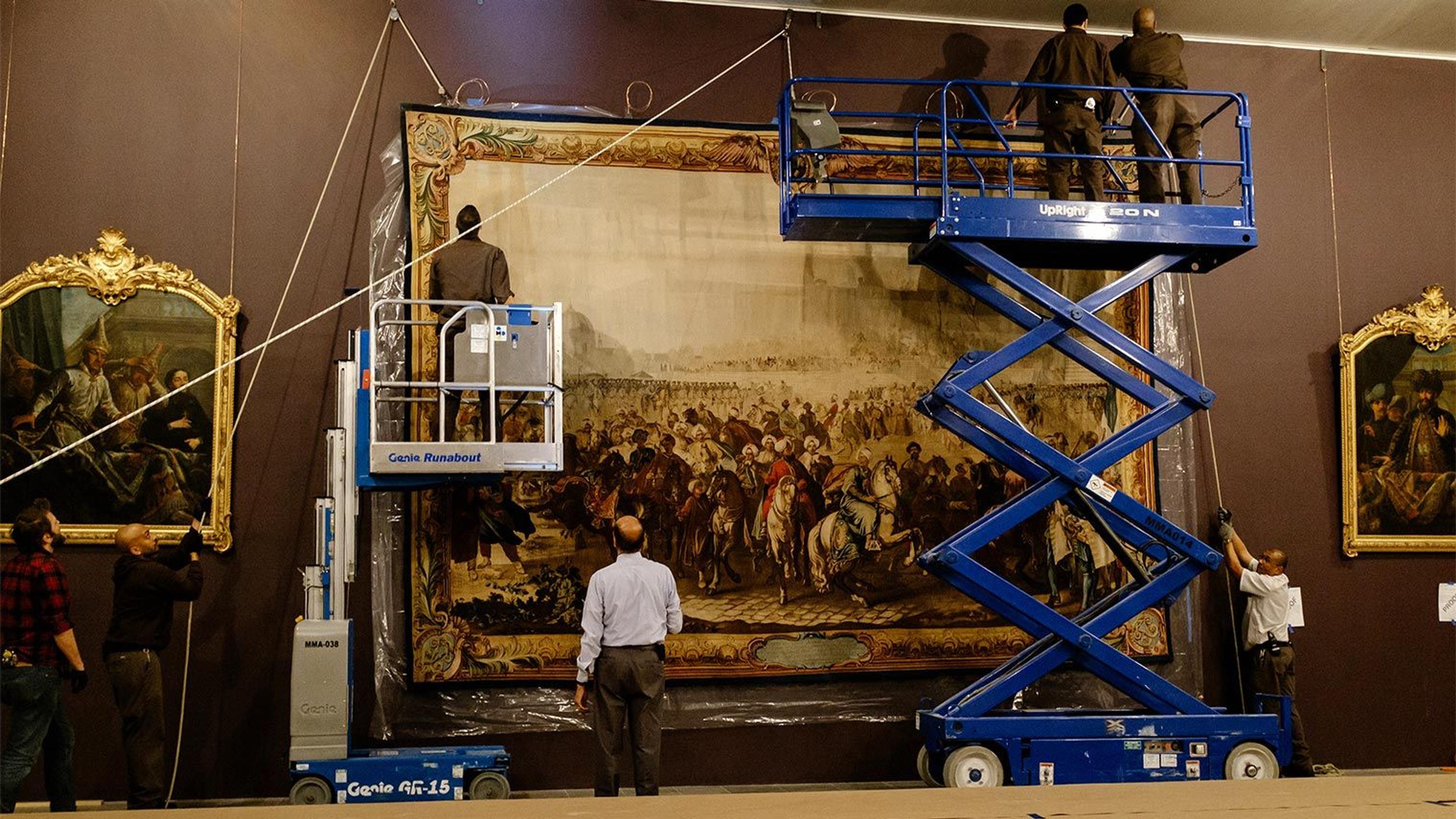 A photo of riggers installing a large tapestry
