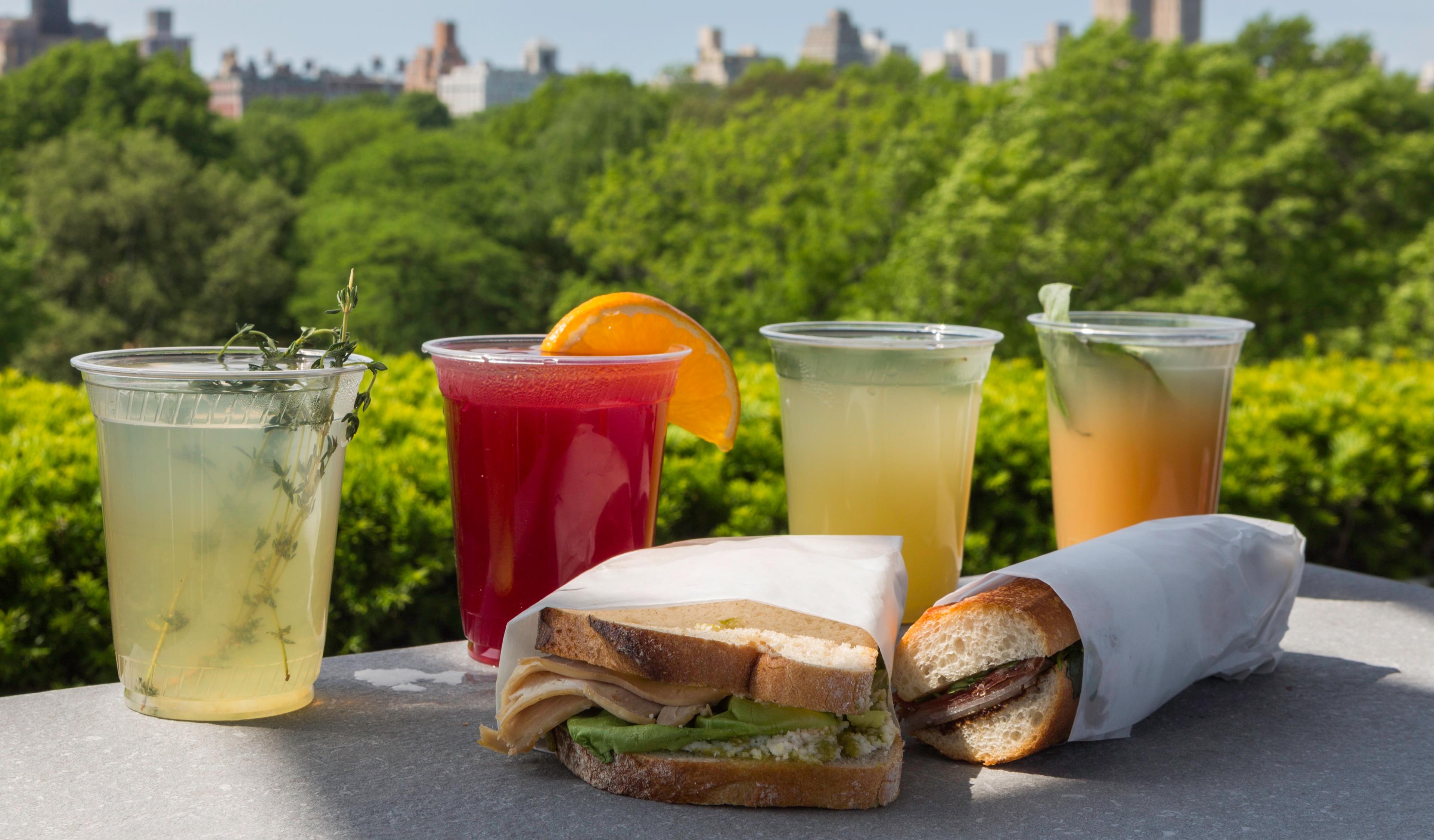 An assortment of sandwiches and drinks against a skyline view.