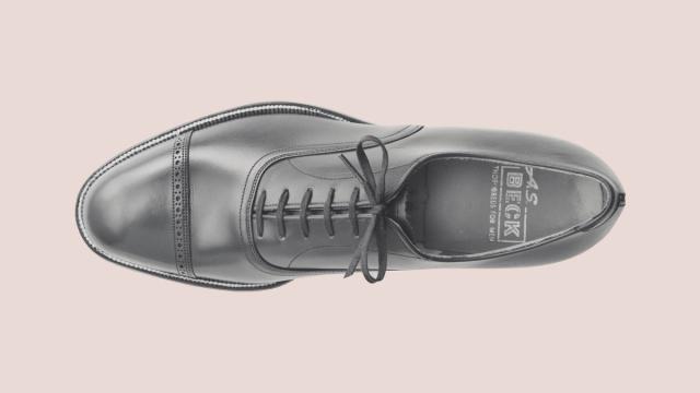 Blush background with a gentlemen's shoe in the center.