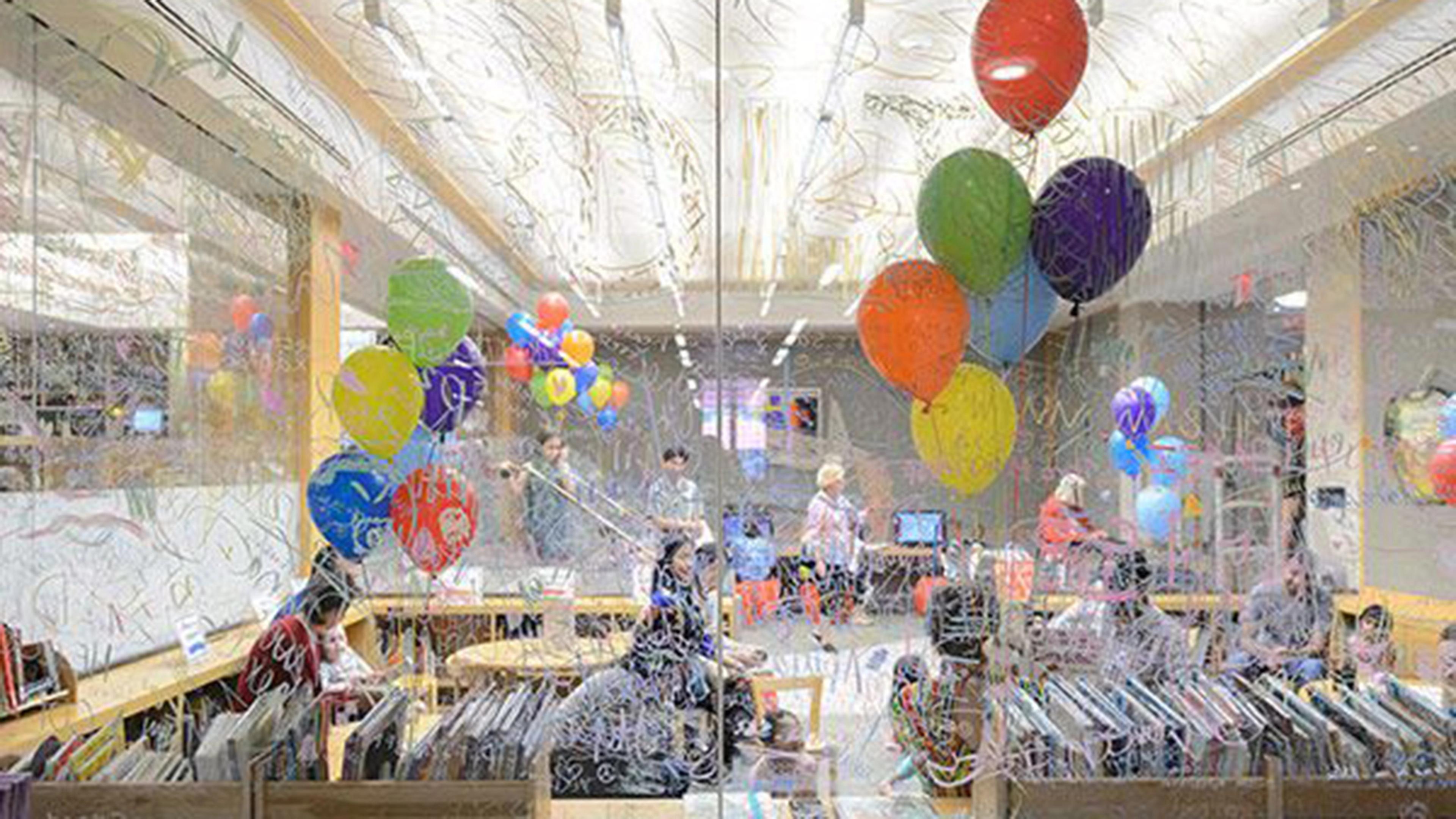 Balloon-filled room with parents and kids, seen through a window.