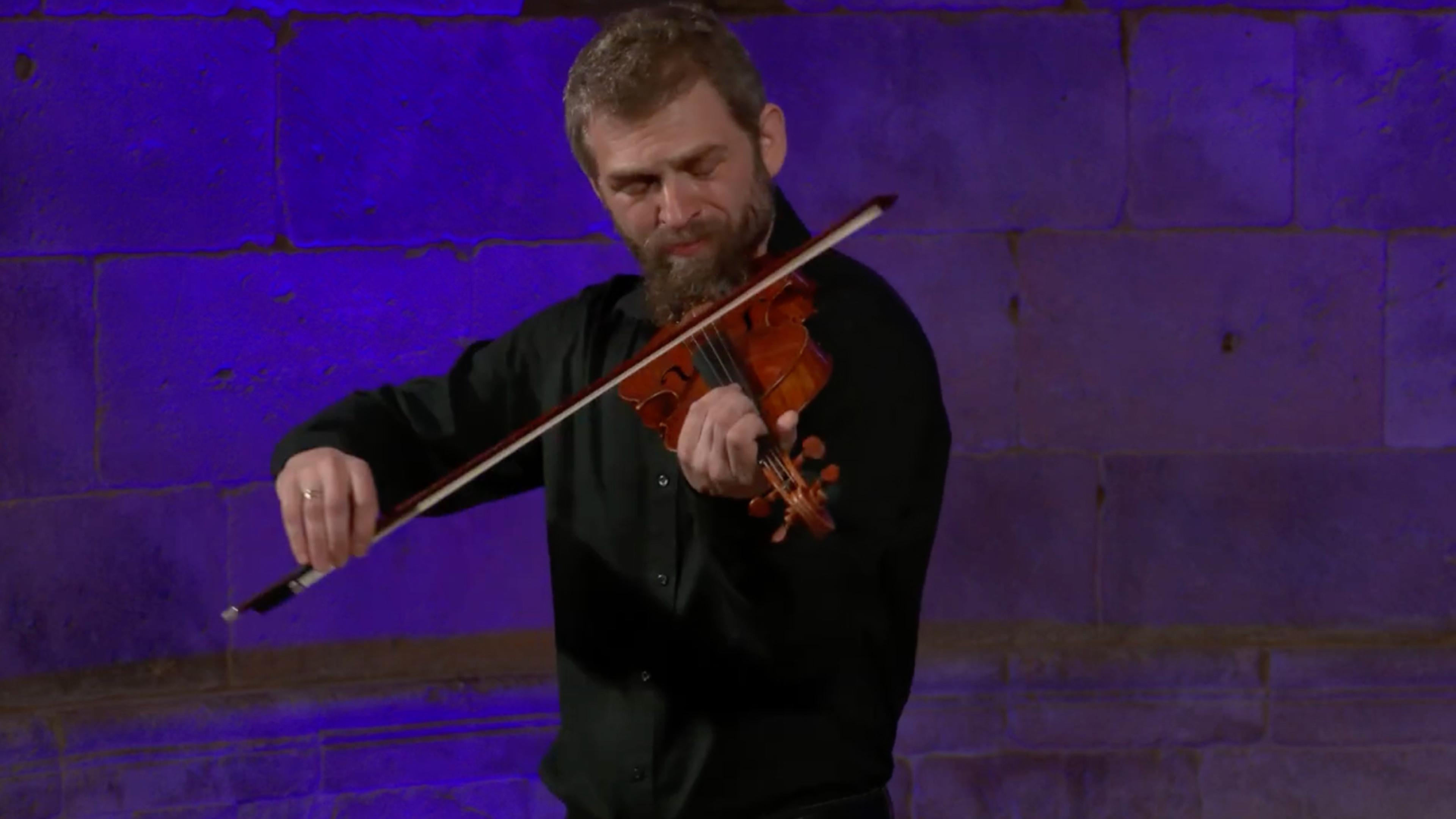 Johnny Gandelsman plays the violin against a purple-lit background