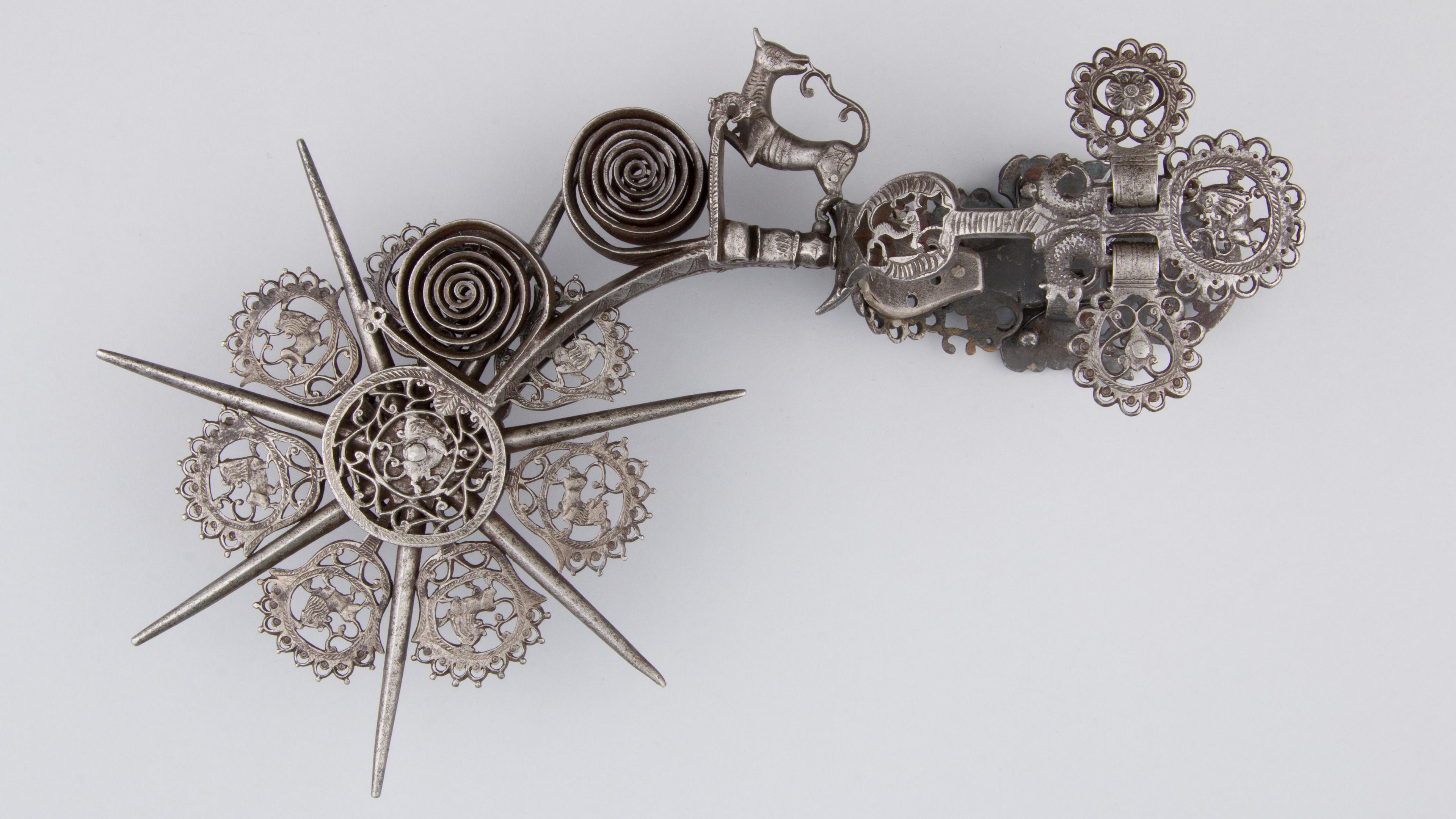 Pair of iron spurs with animal motifs, including lions, eagles, and dogs, interspersed between spikes.
