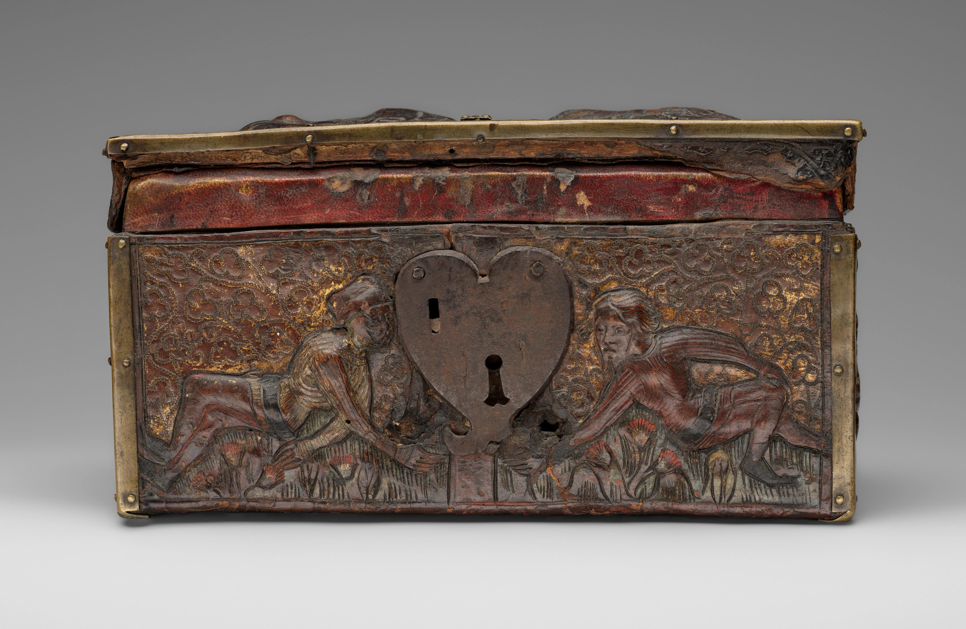 Small box with a heart-shaped keyhole framed by two carved figures, who reach out towards each other.