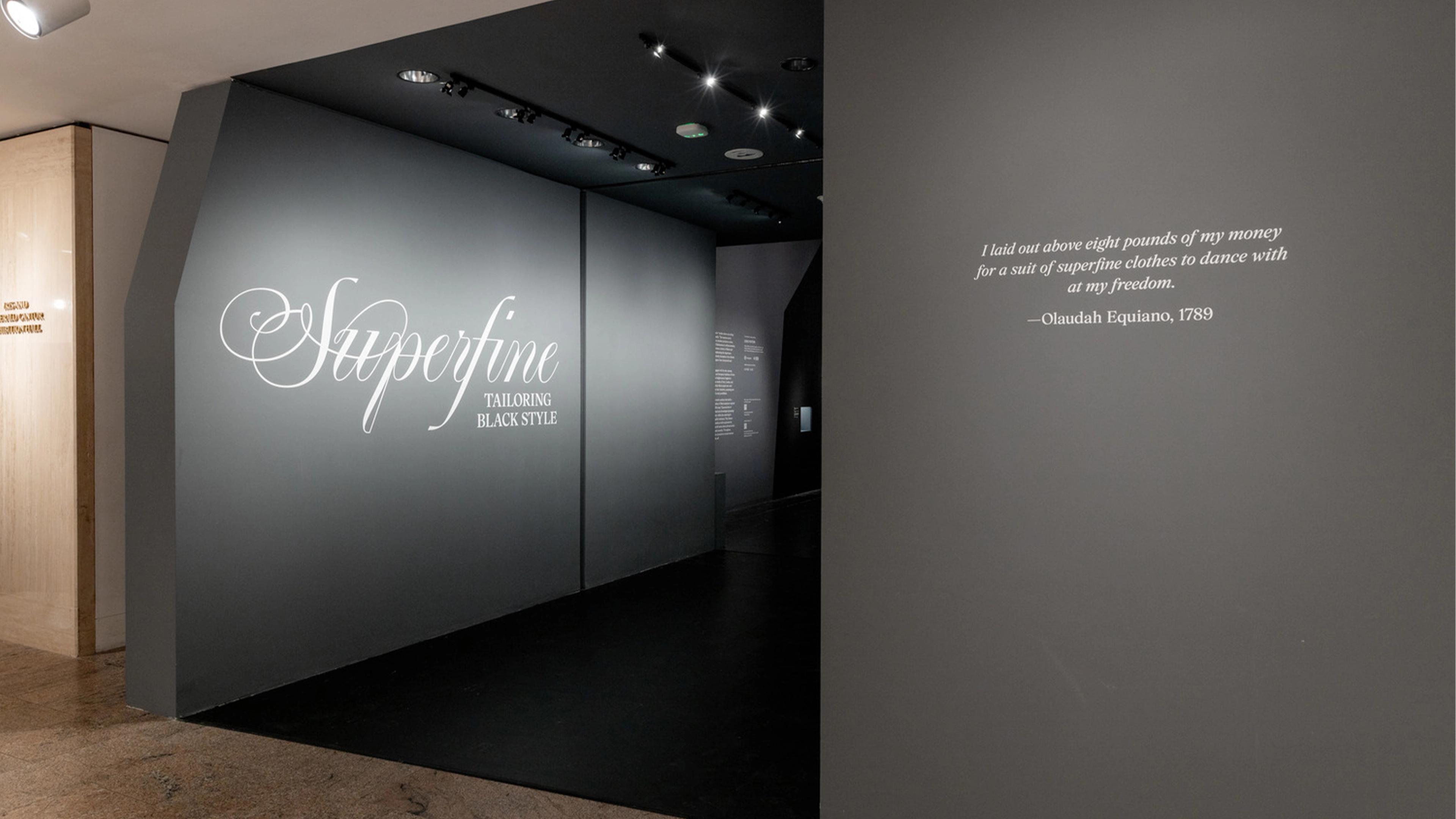 Exhibit entrance with elegant script "Superfine: Tailoring Black Style." A quote by Olaudah Equiano, 1789, expresses empowerment through fashion.