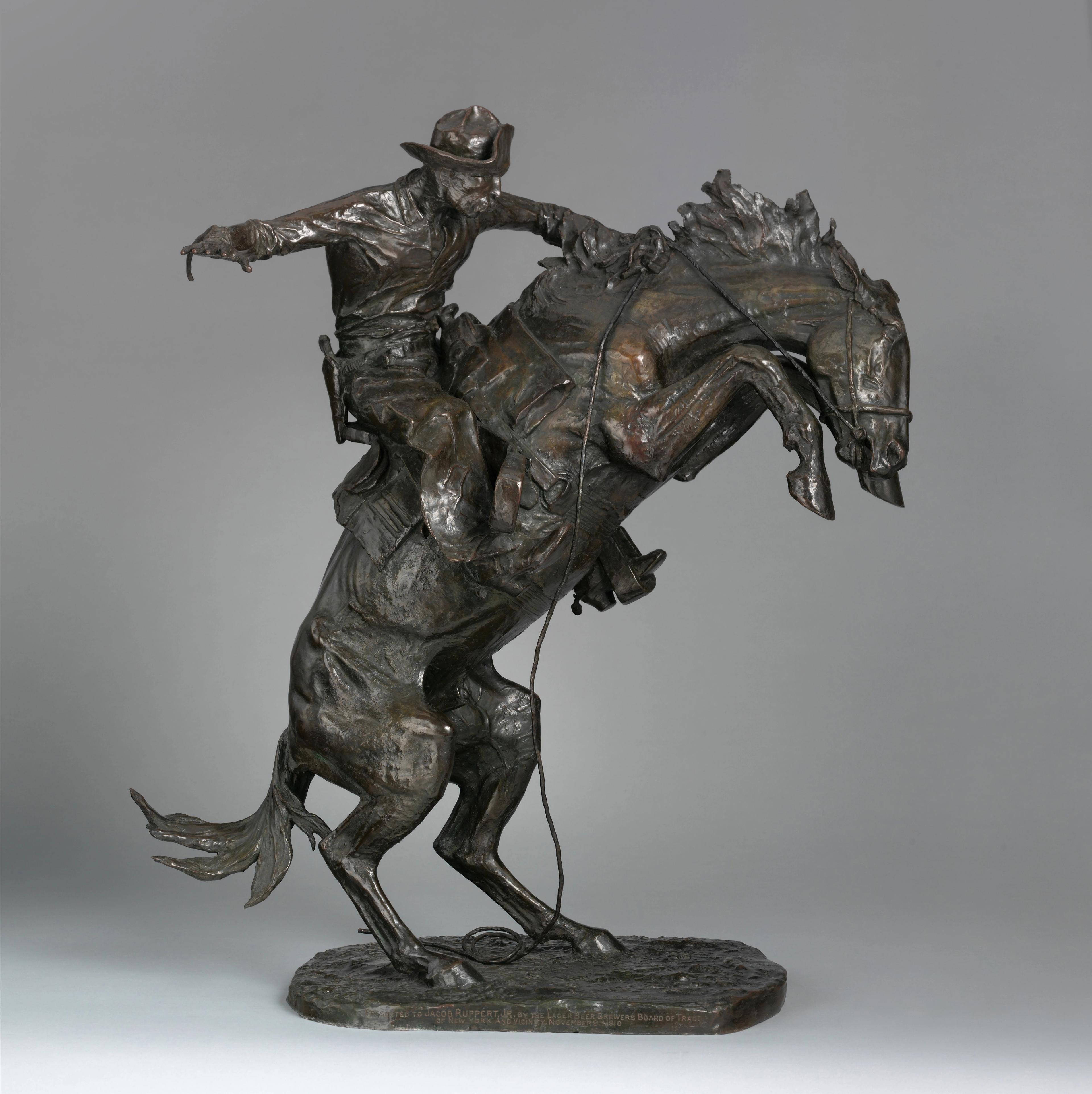 A bronze sculpture of a cowboy riding a bucking bronco