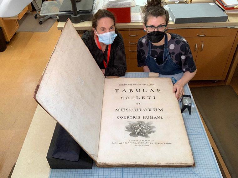 Books conservation staff with large book