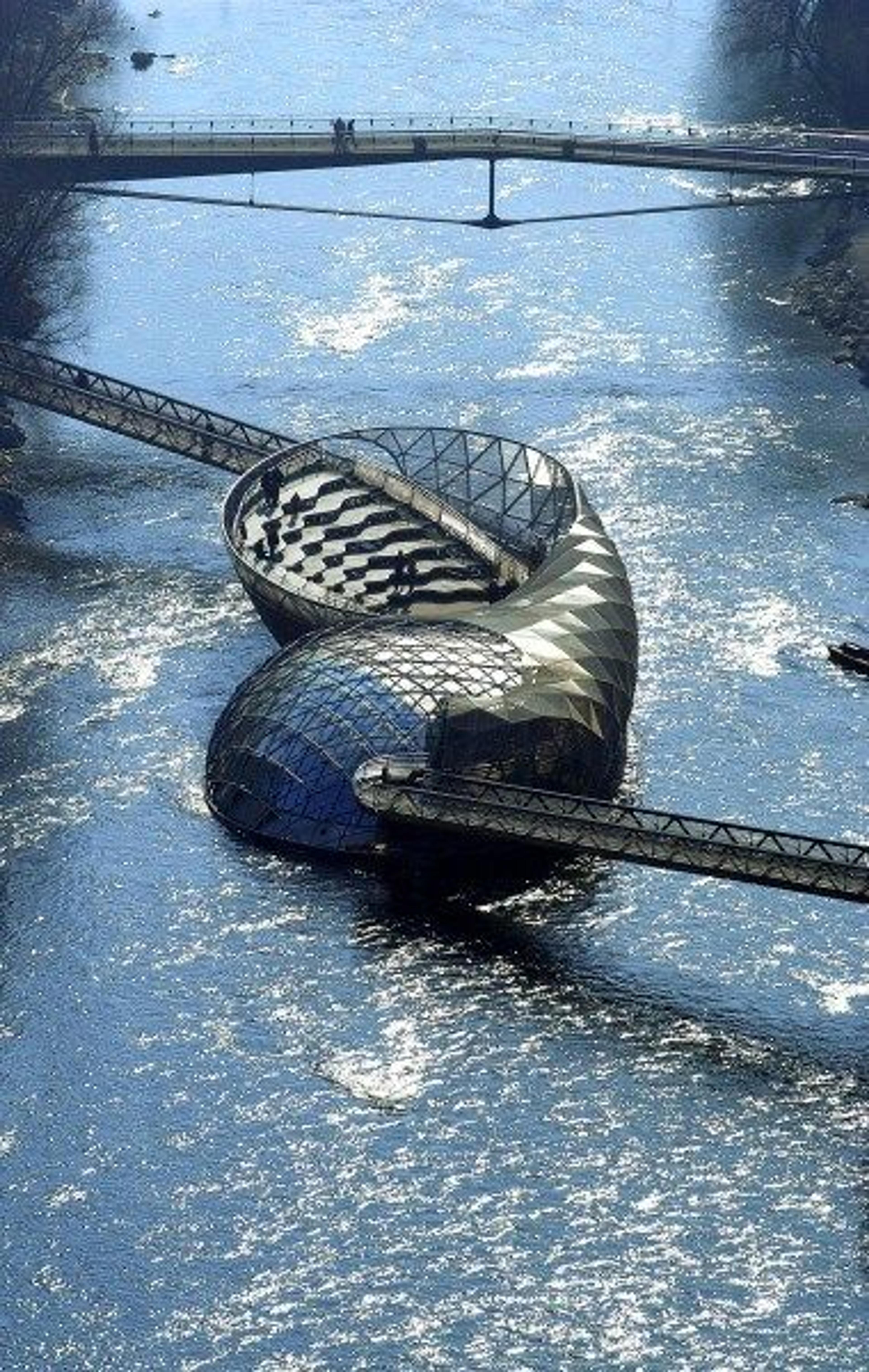 Installation in Graz, Austria by Vitto Acconci titled MUR ISLAND, made of steel, glass, rubber, asphalt, water, light; 1,052 square meters.