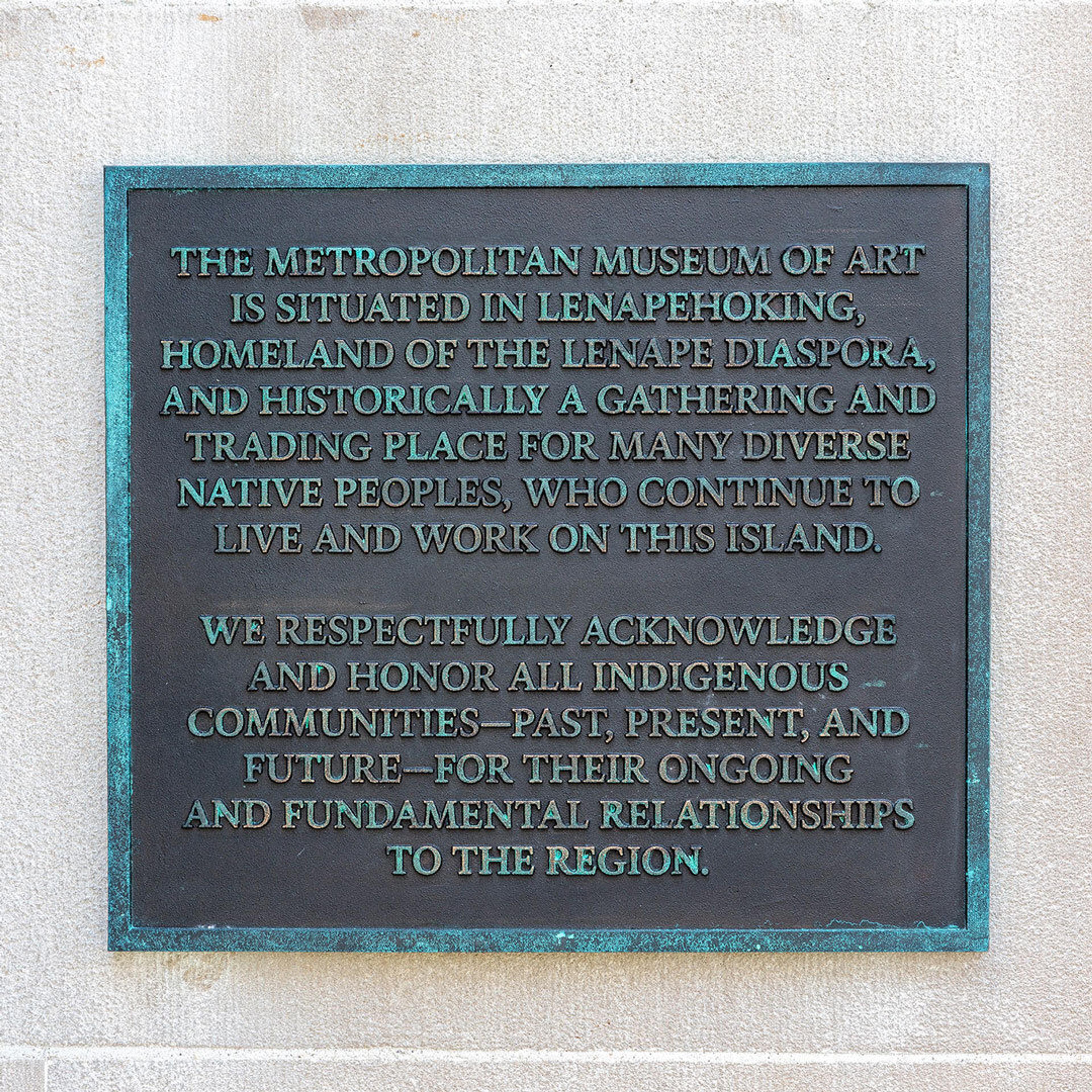 A bronze plaque mounted on the facade of The Met
