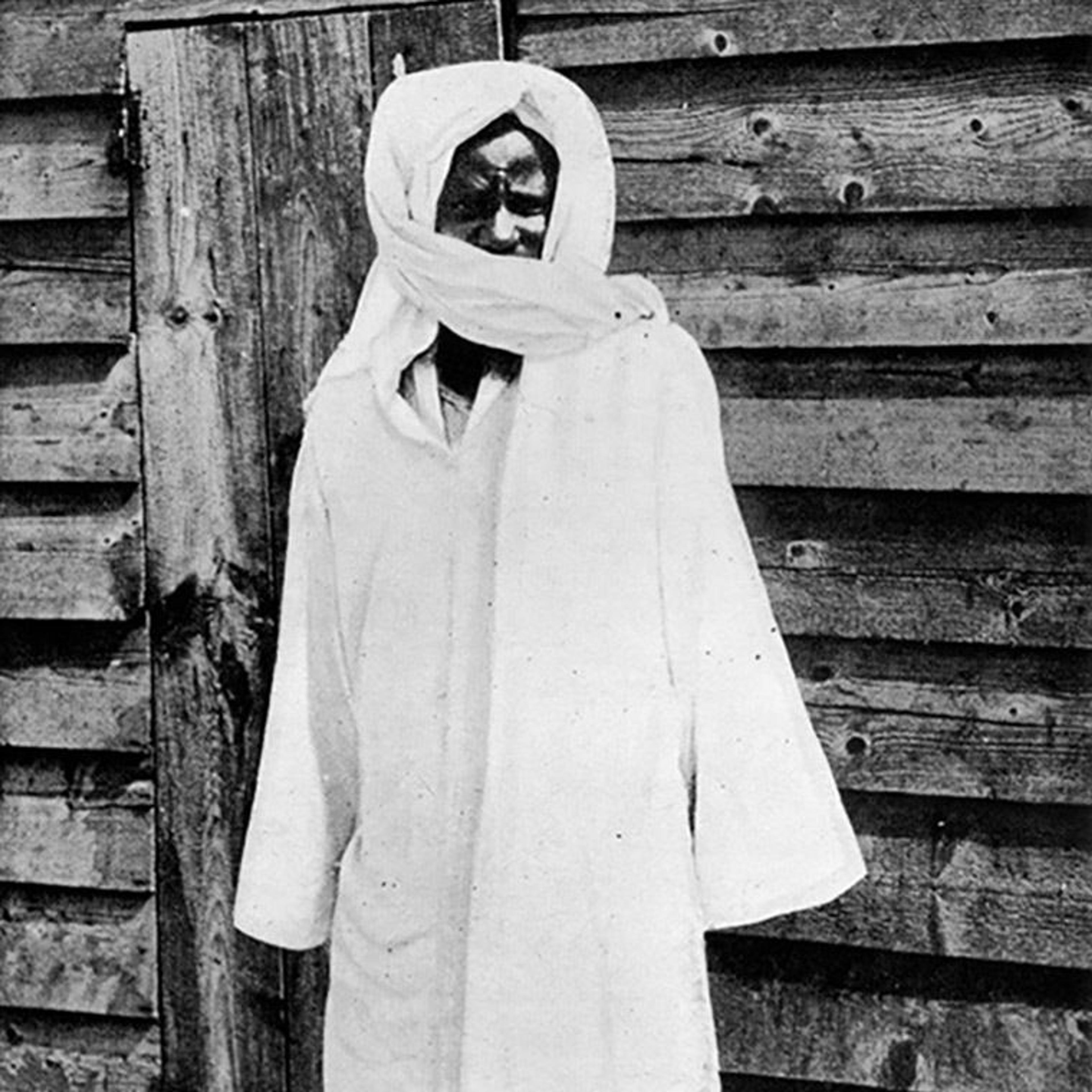 A black-and-white photo of a man shrouded in all-white cloth