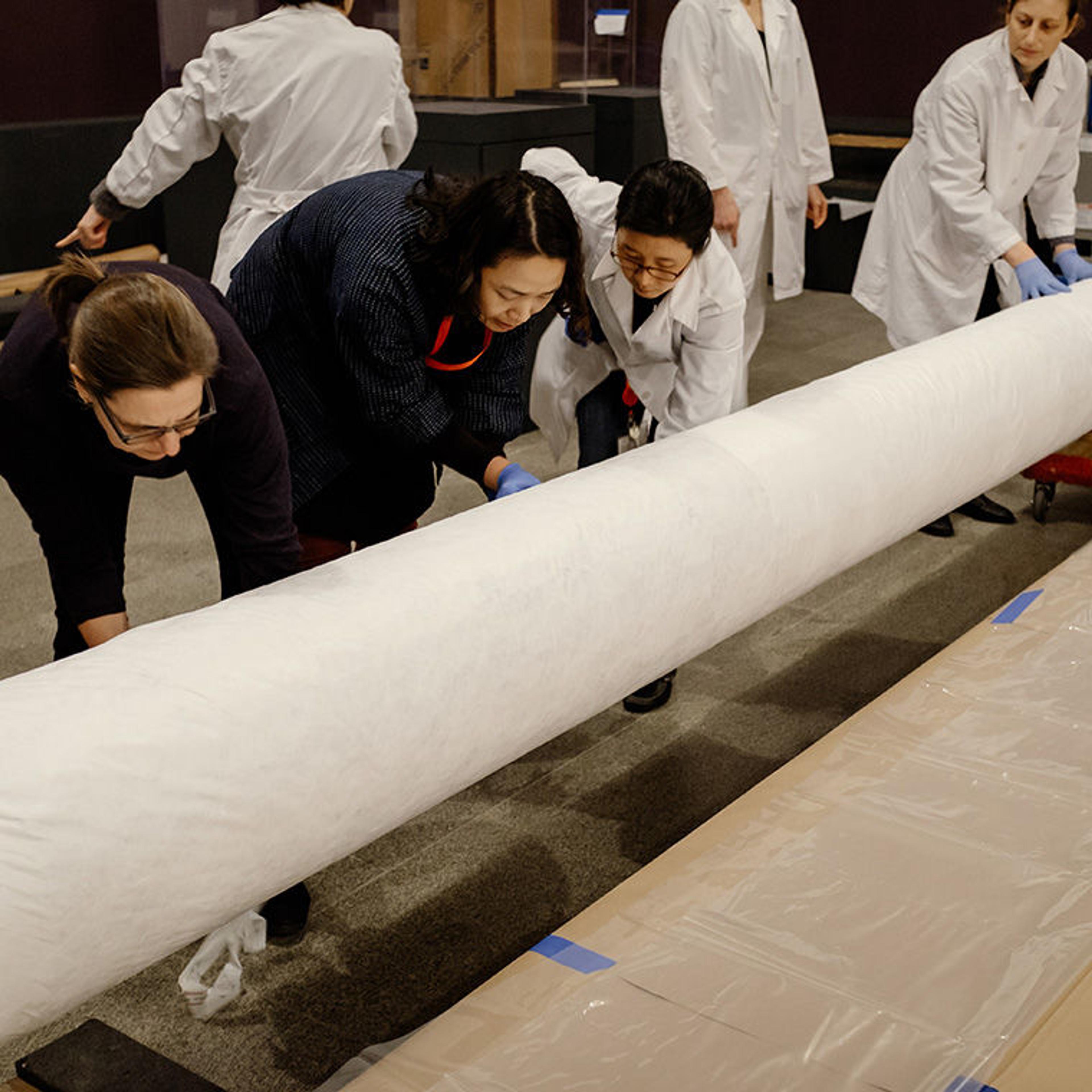 Staff from The Met unroll a work of art for installation in the exhibition Visitors to Versailles