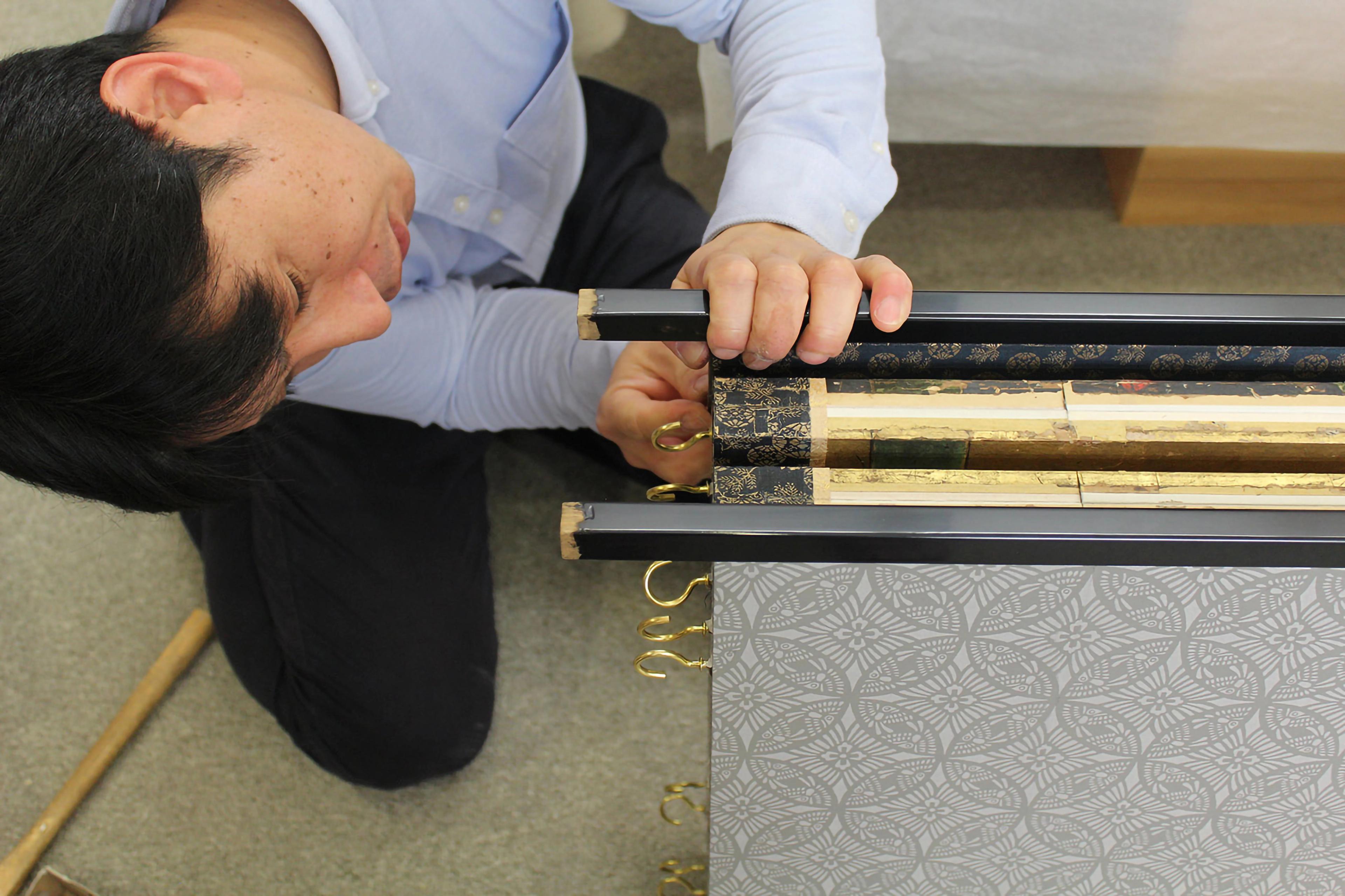 Visiting conservator from Japan kneeling and examining an artwork