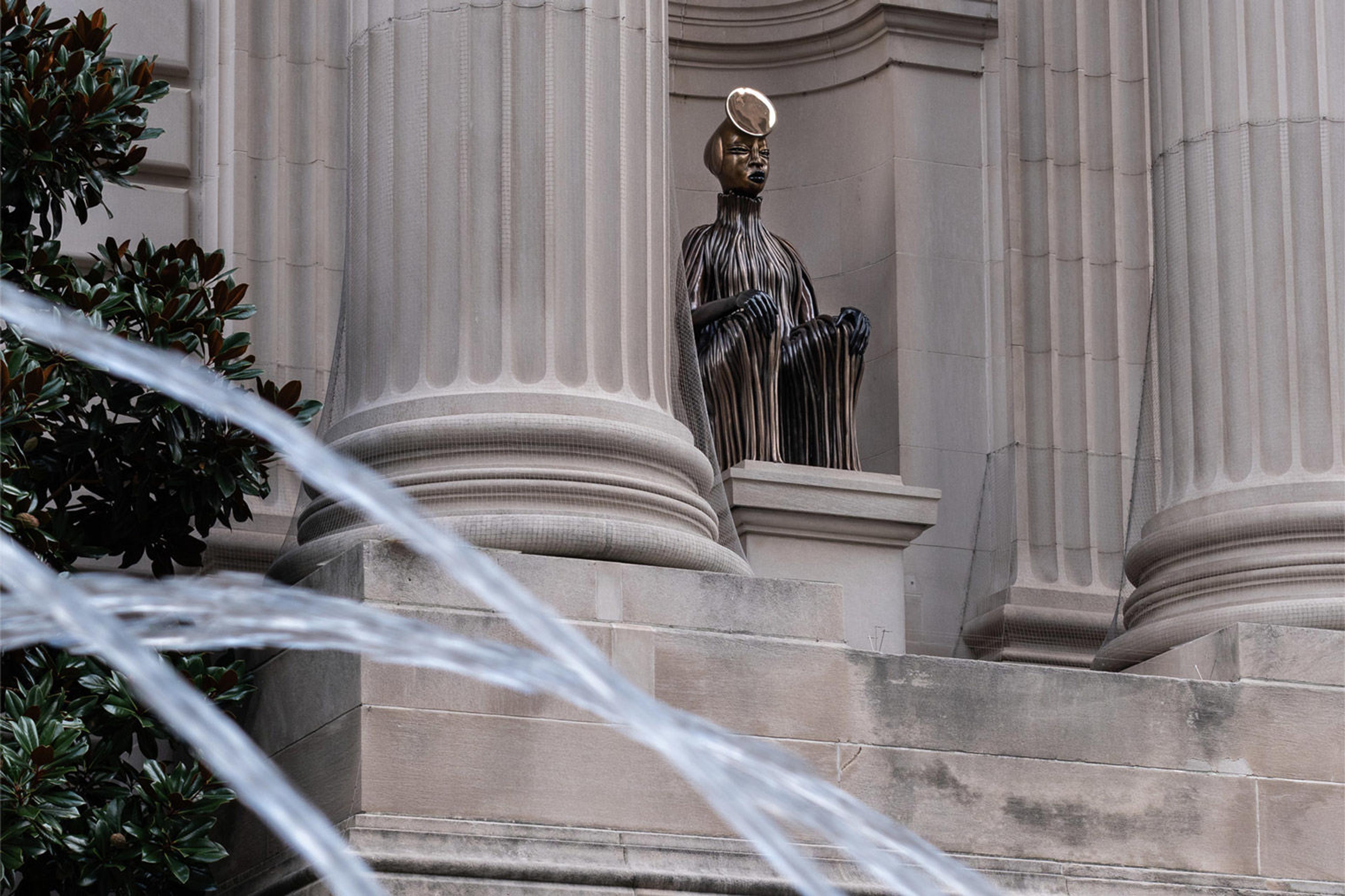 A bronze figure sits in the Metropolitan facade