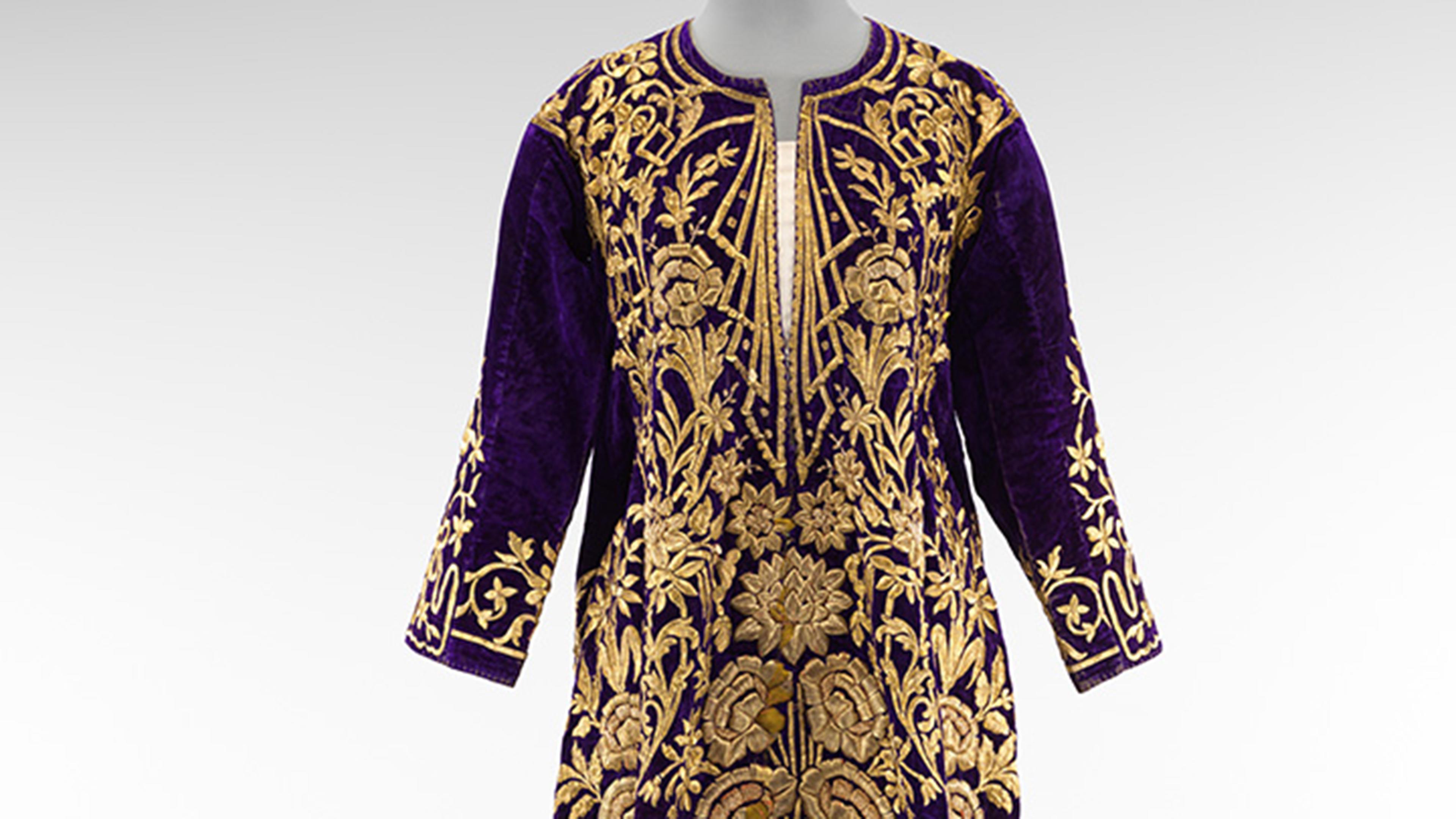 Image shows the top half of an Ottoman wedding dress known as a bindalli, made of purple velvet with gold embroidery and set against a gray background.