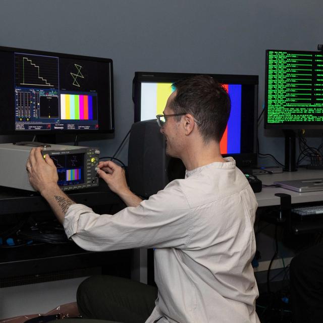 A person working in a media lab operating electronic equipment.