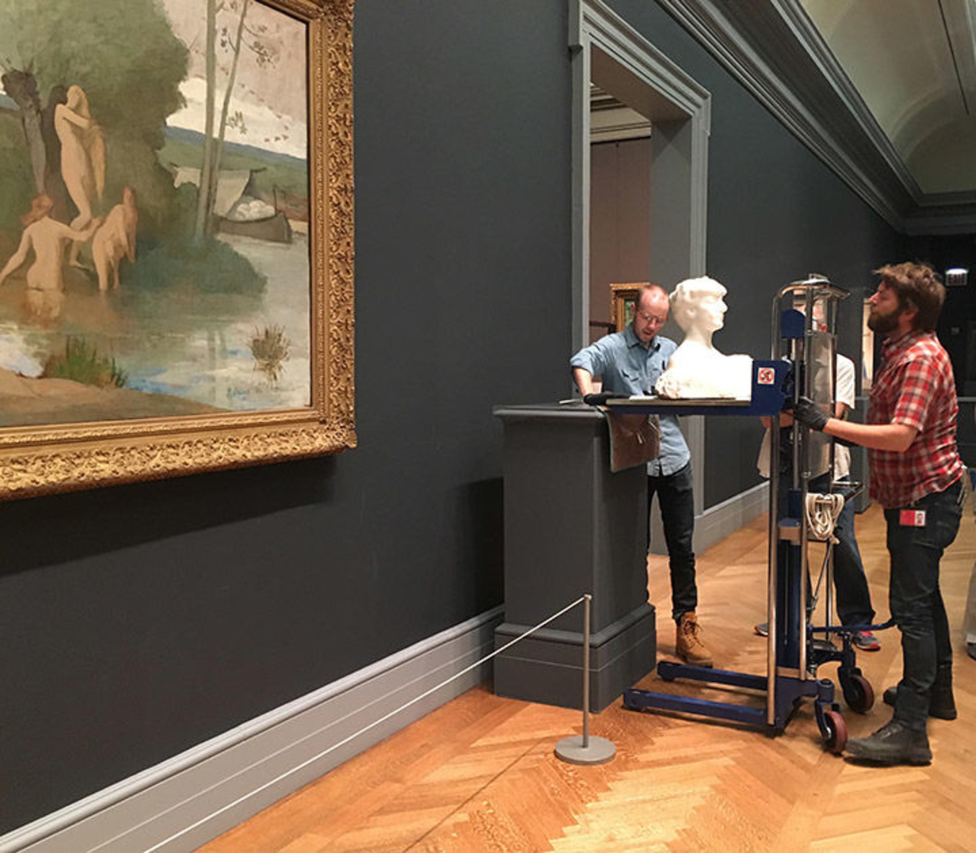 Museum technicians William Winks and Juan Stacey install Rodin's marble bust Madame X next to Puvis's The River