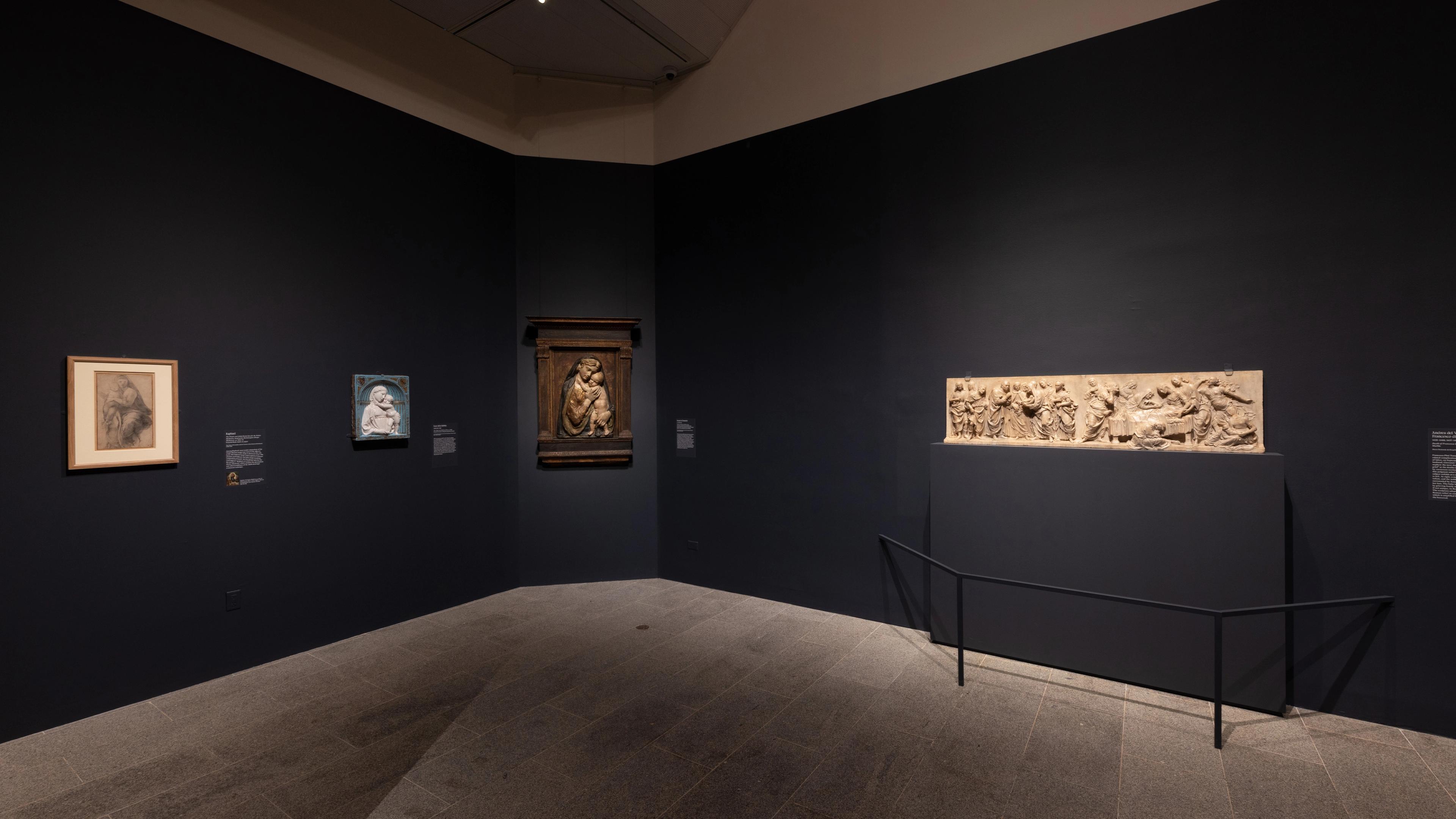 Dimly lit art gallery with dark walls showcasing framed sketches and a central intricate artwork.