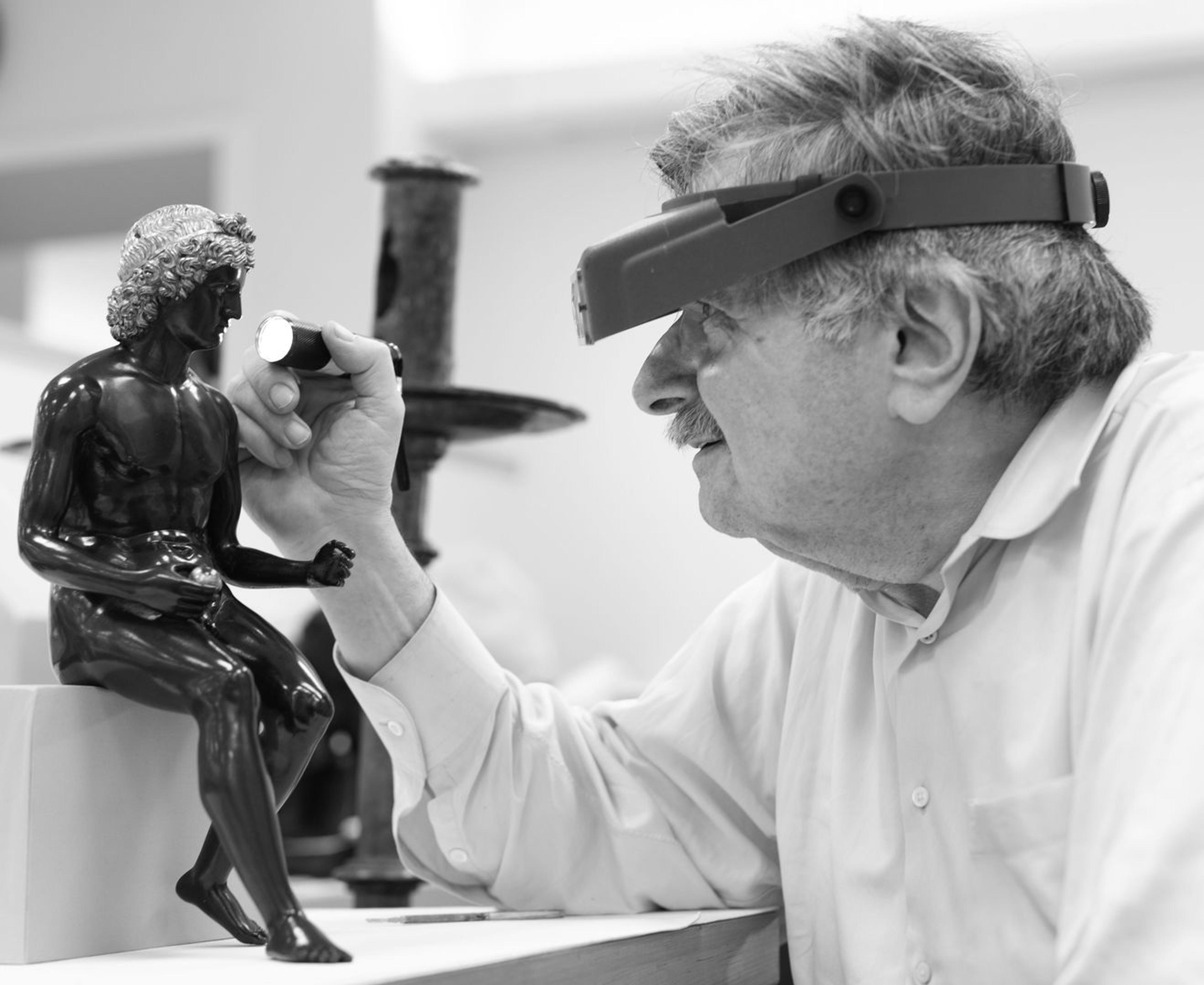 Conservator Dick Stone examining bronze sculpture Antico Paris with headloop and flashlight