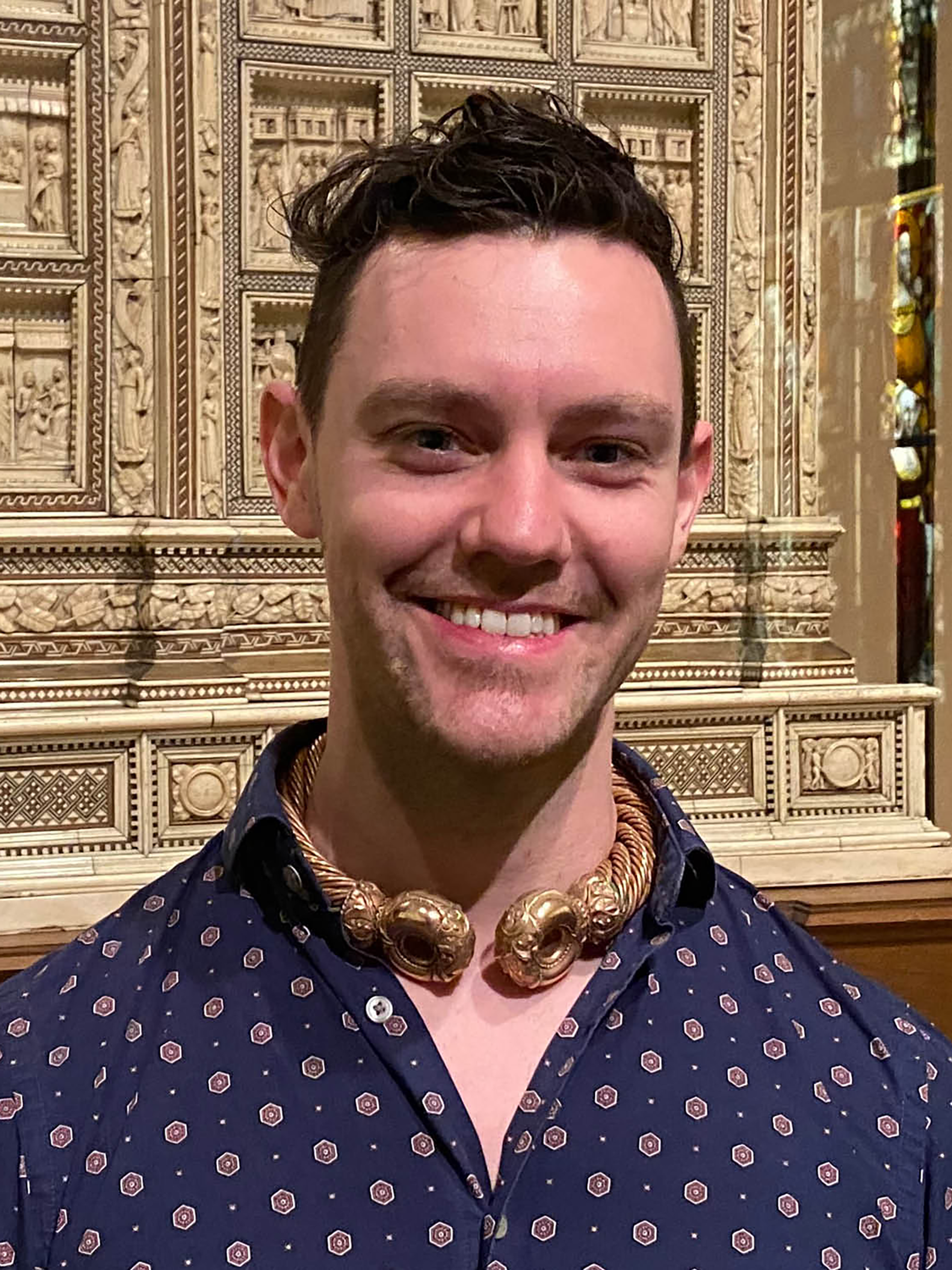 A man wearing a navy shirt stands in an art museum gallery