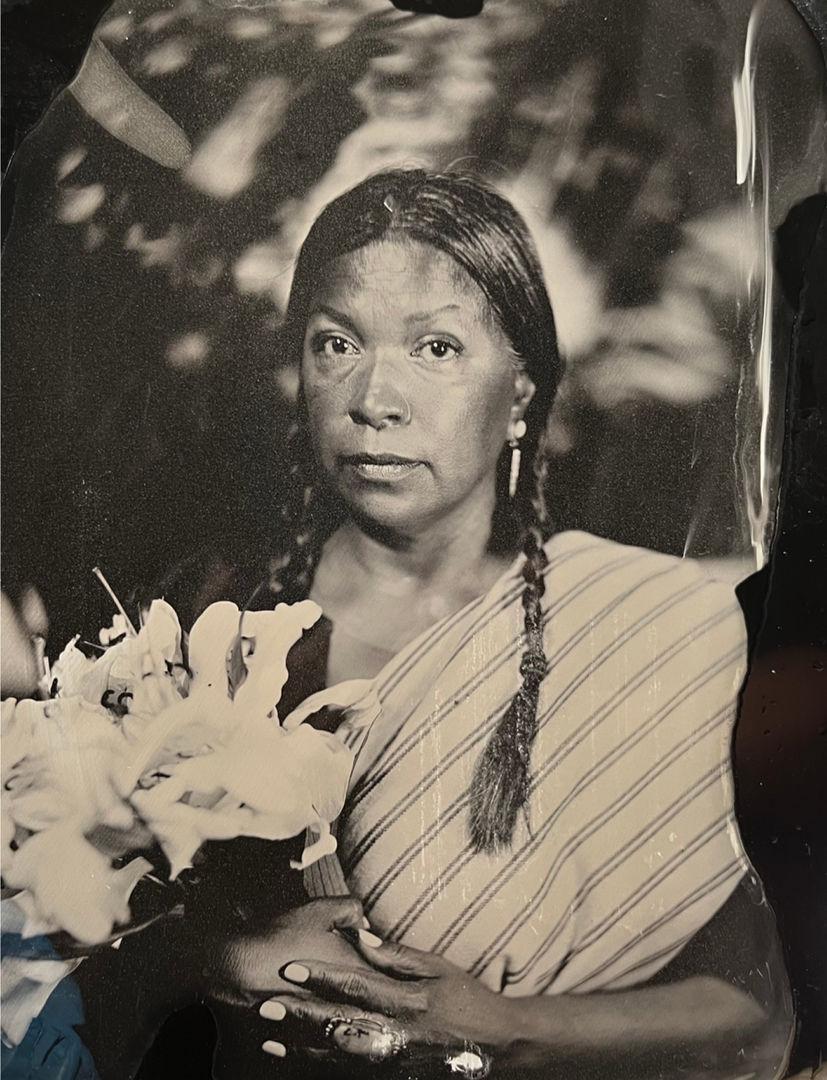 Black and white portrait of Patricia Norby holding flowers and looking towards the camera