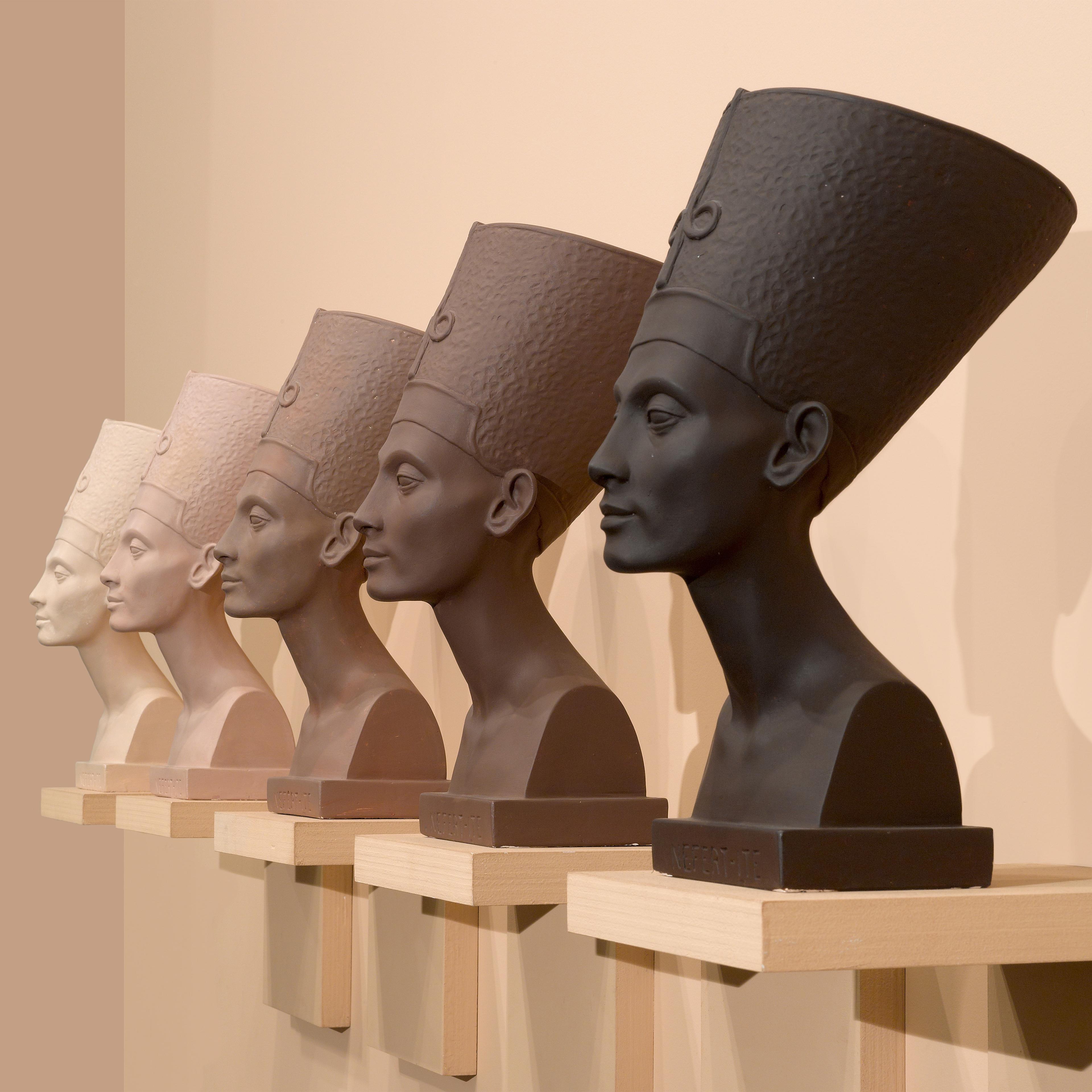 Four Traditional Egyption stone heads mono colored from the darkest brown to a lighters shade lined up against the wall.
