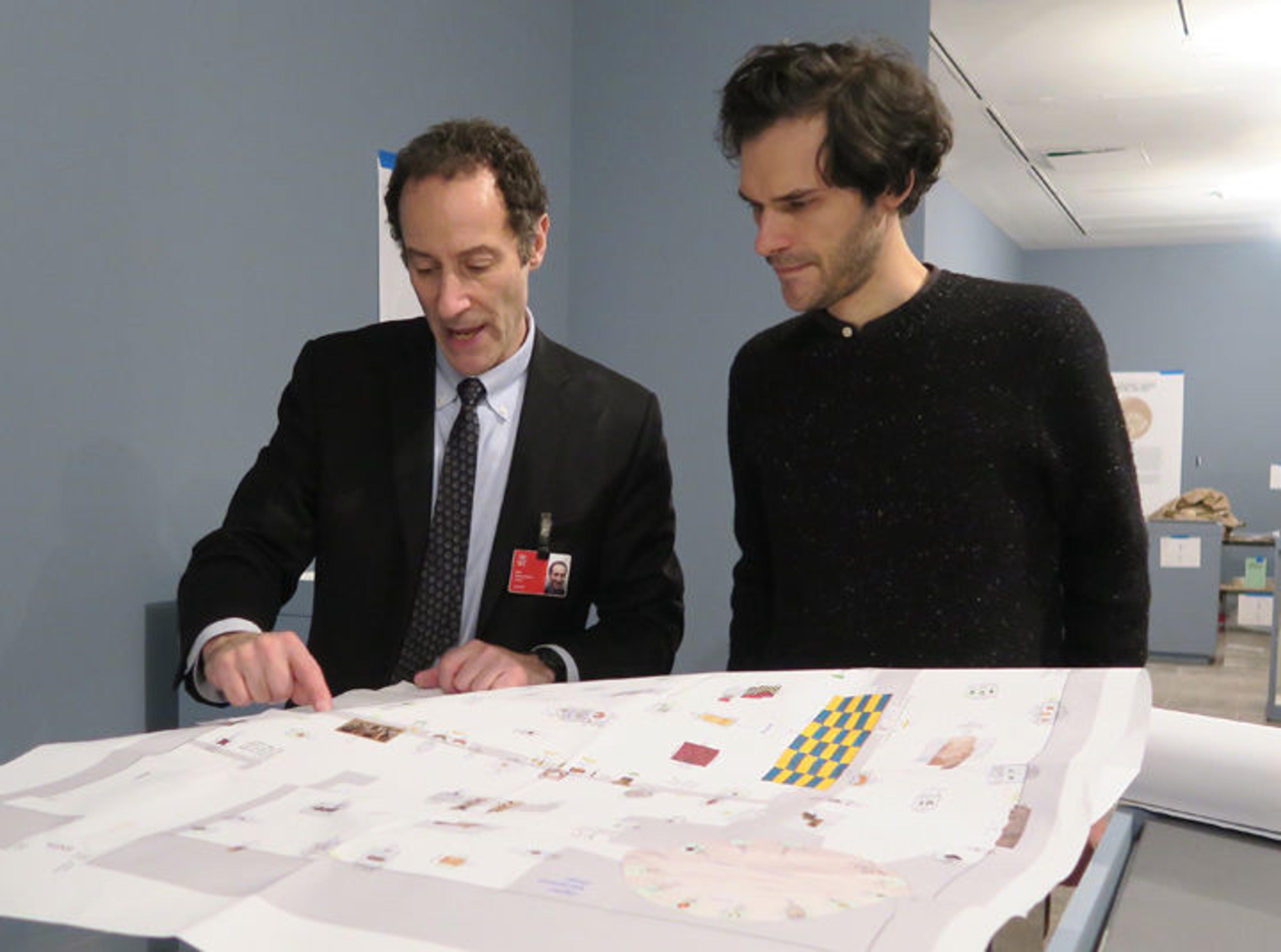 Two designers look at a floor plan for an exhibition gallery