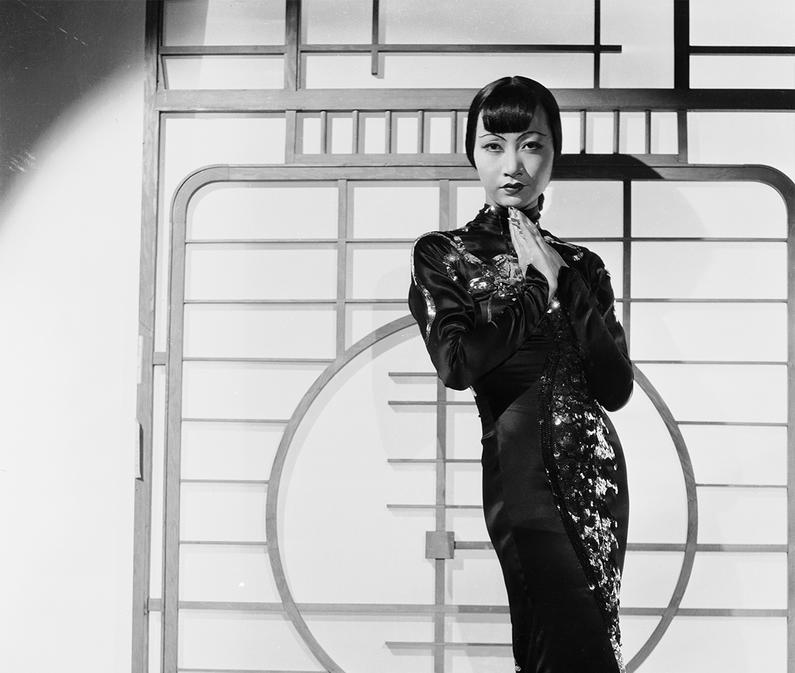 Black and white photo of woman posting where wearing a tradition Asian style dress.