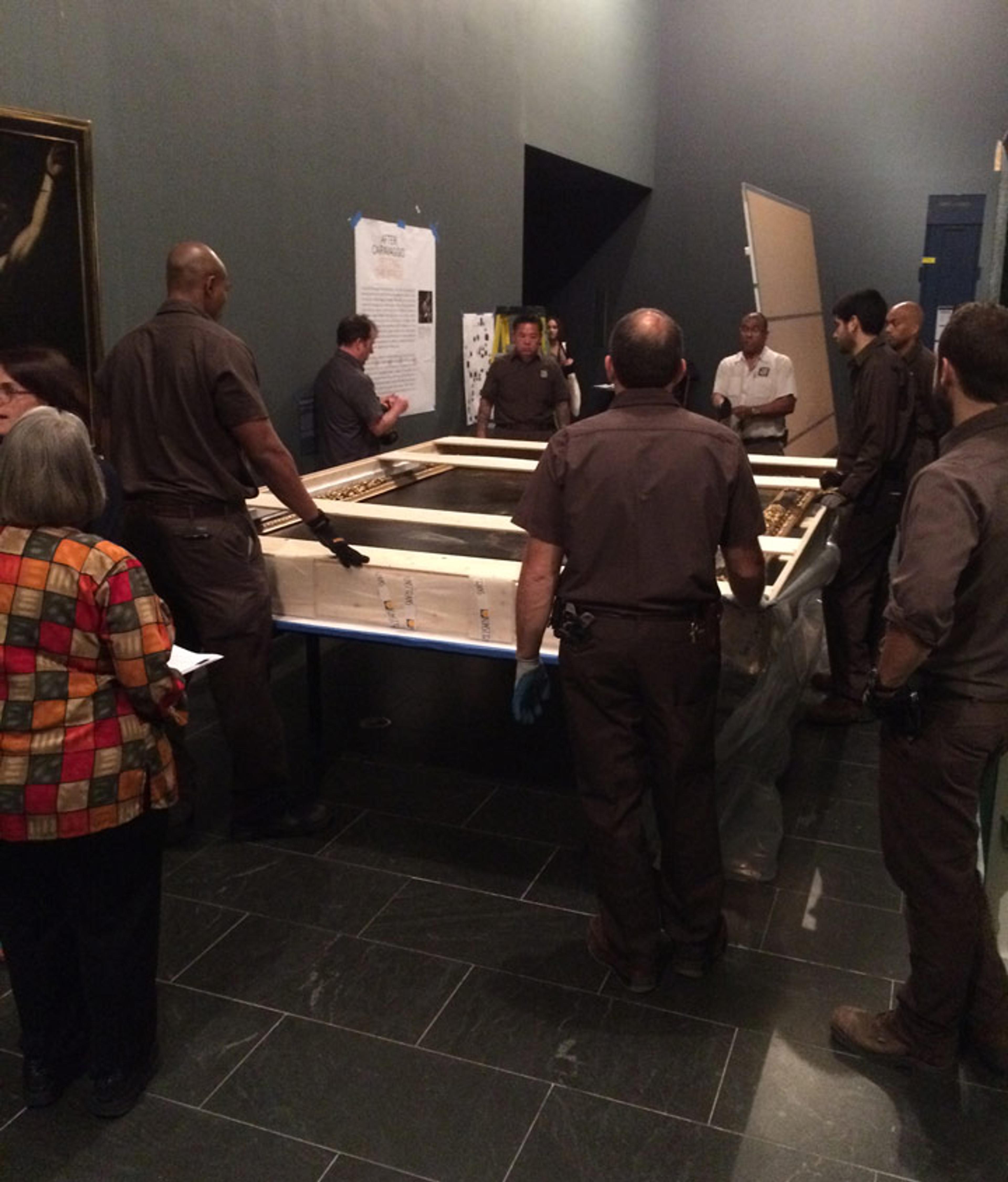 A group of technicians prepare to remove a Valentin de Boulogne painting from its shipping crate