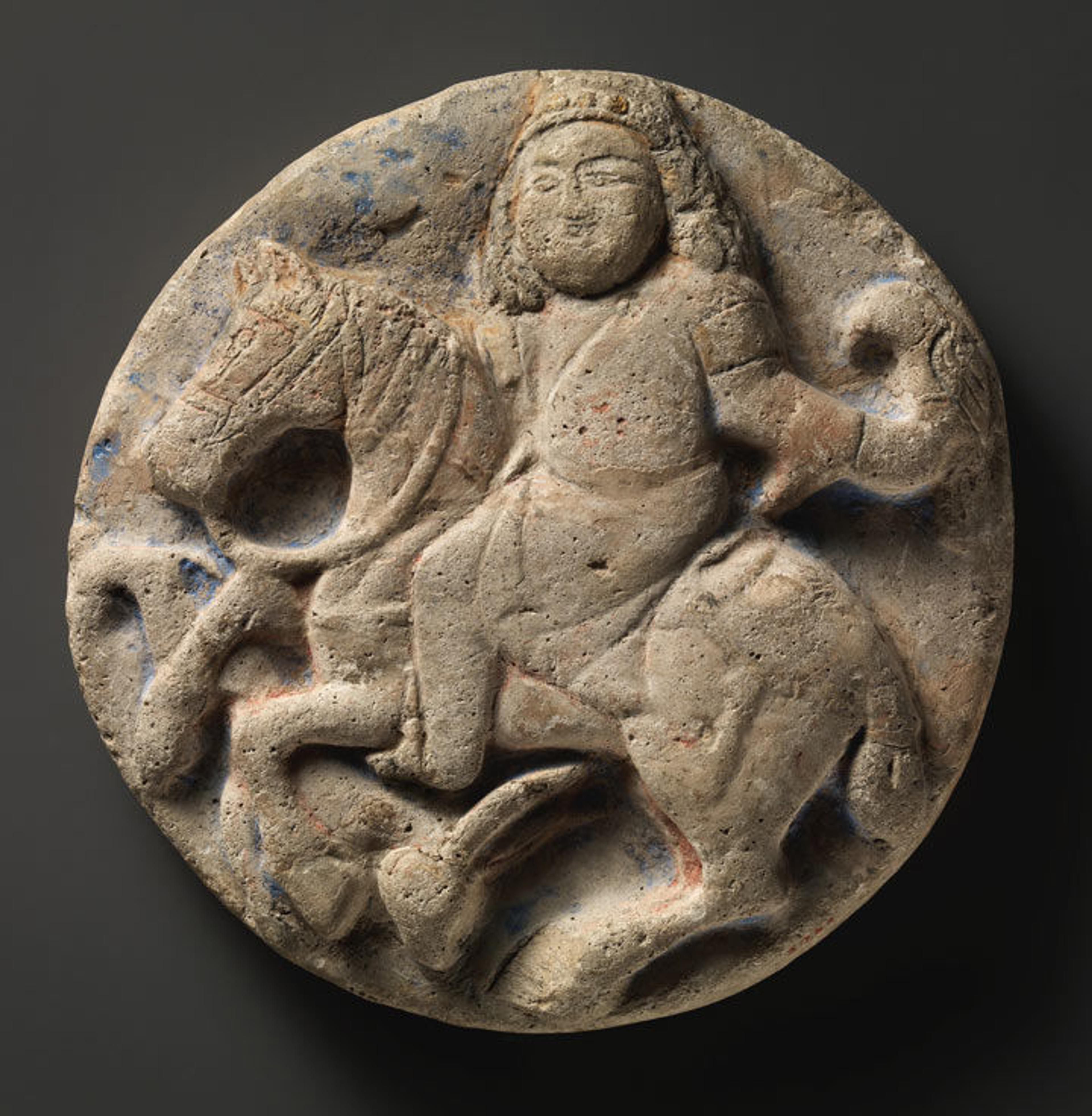 A plaster roundel depicting a man on a horse holding a falcon