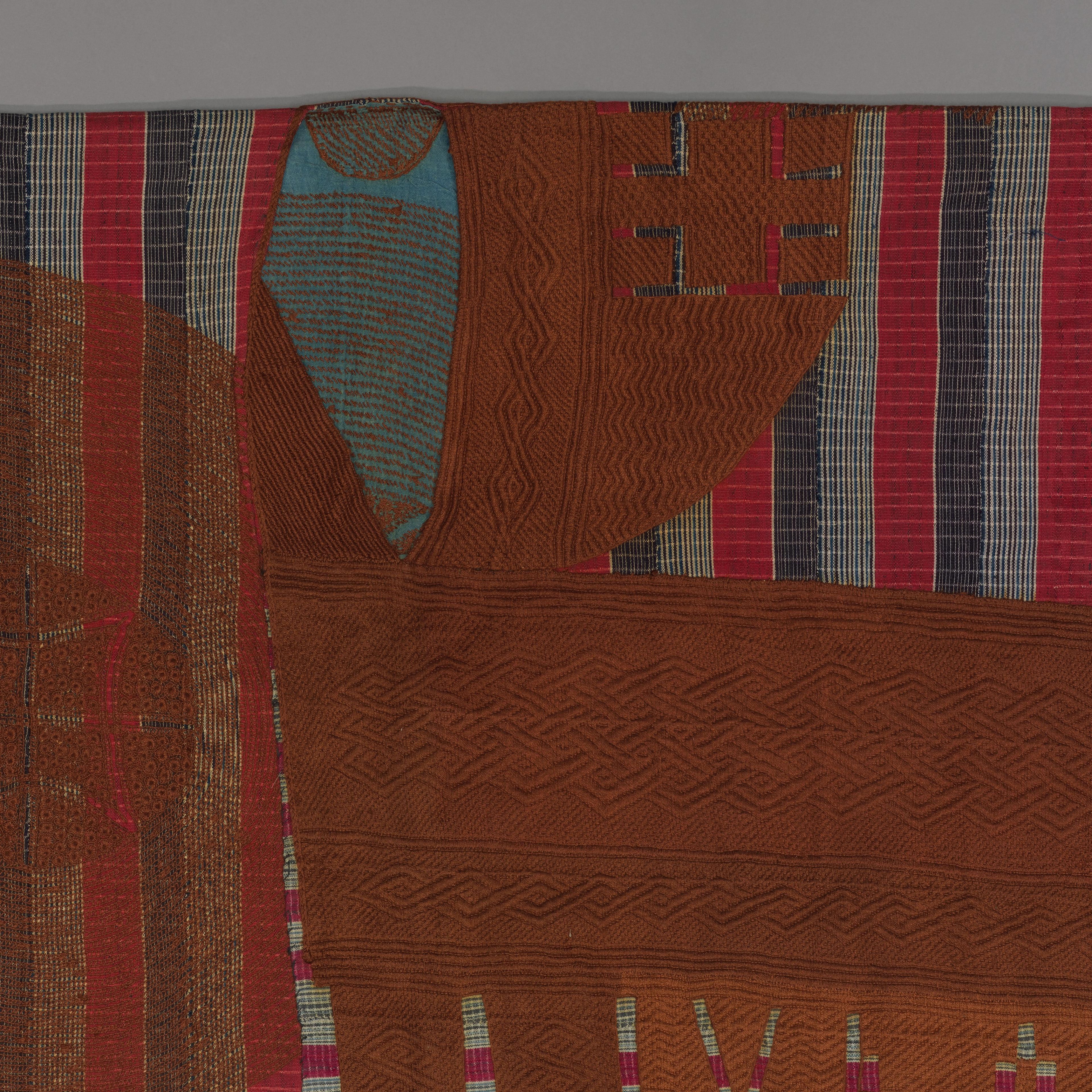 Detail of a striped robe in red, blue, and white with a central panel featuring abstract shapes and patterns.