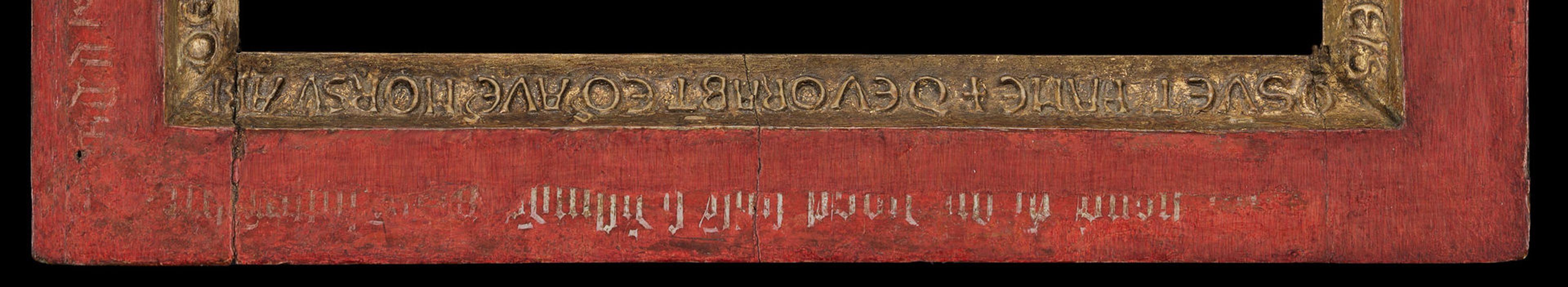 Detail view of a frame with red paint and a gold-gilded outline with text
