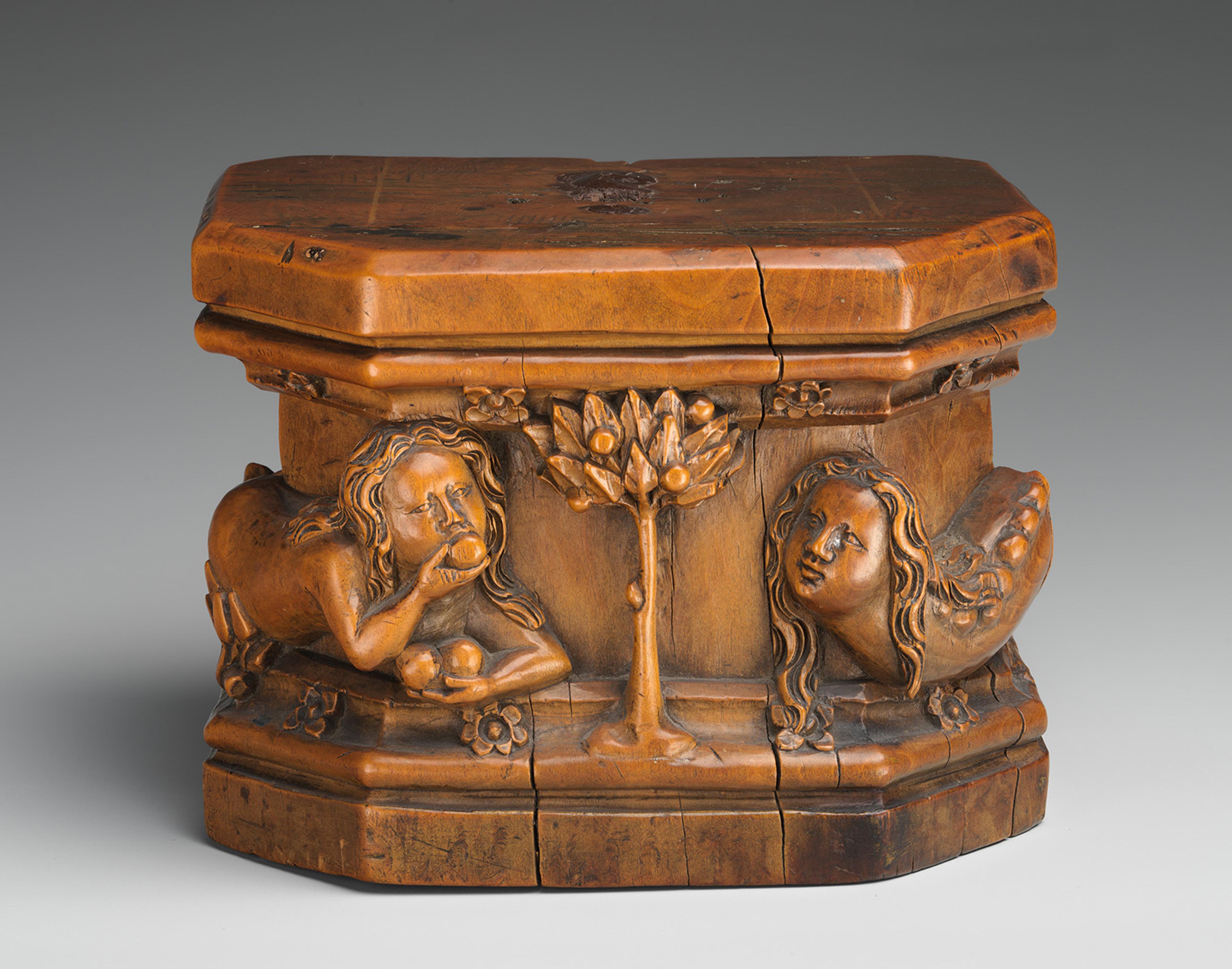 A small wooden carved box featuring figures and a tree in relief.