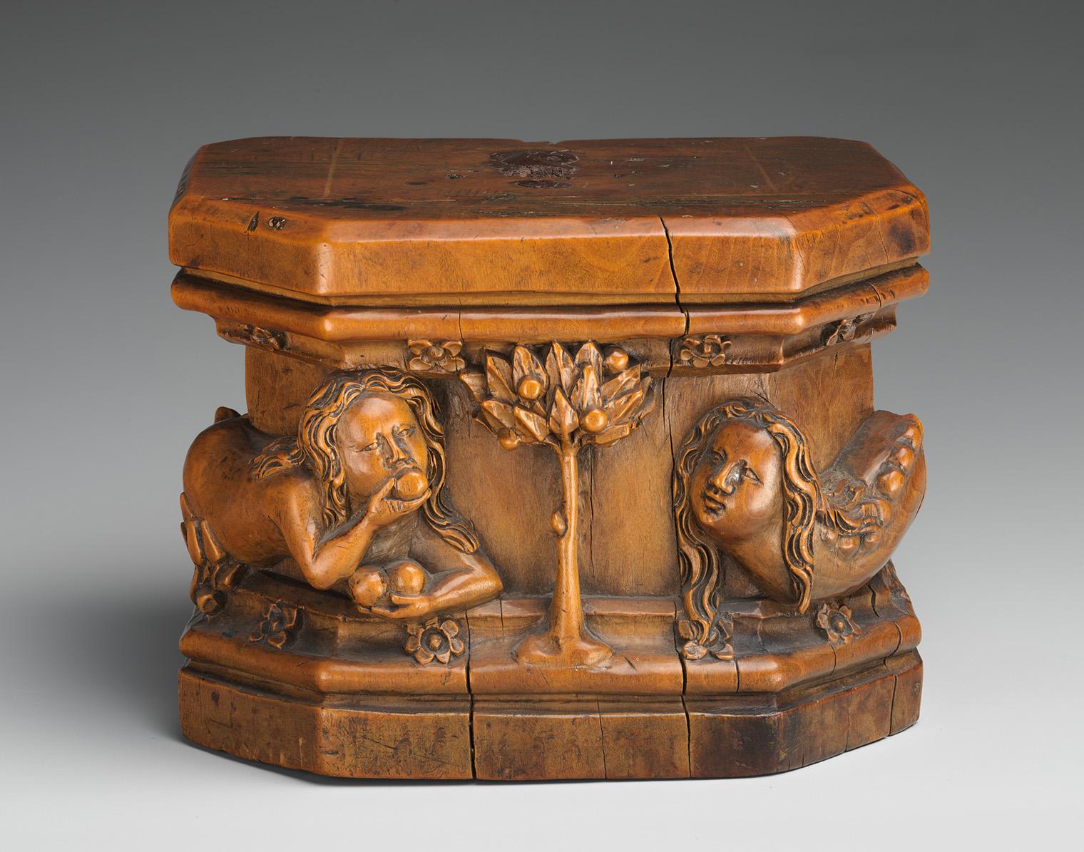 A small wooden carved box featuring figures and a tree in relief.