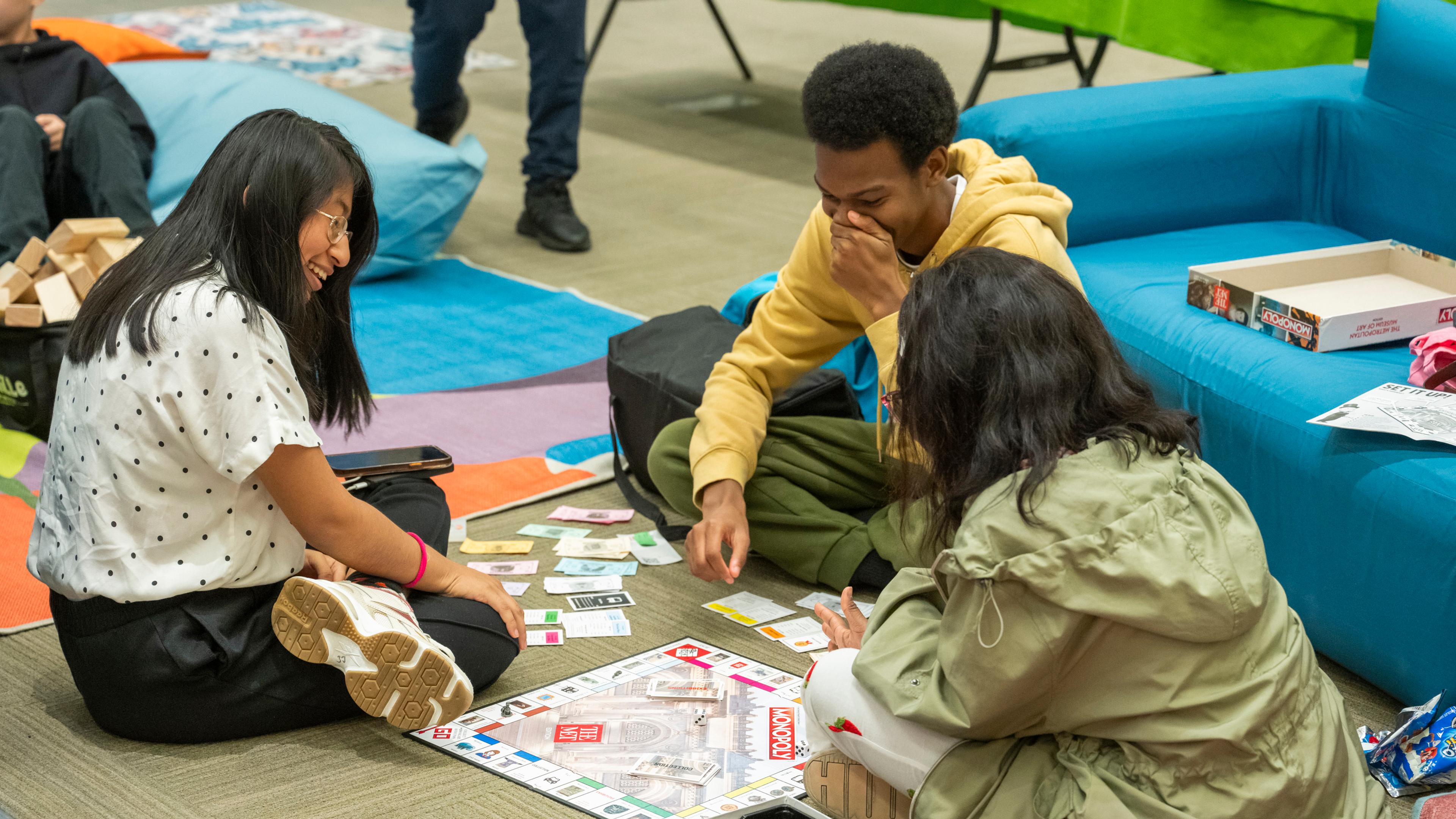 Group of Teens playing a game of Met-themed Monopoly at the Museum.
