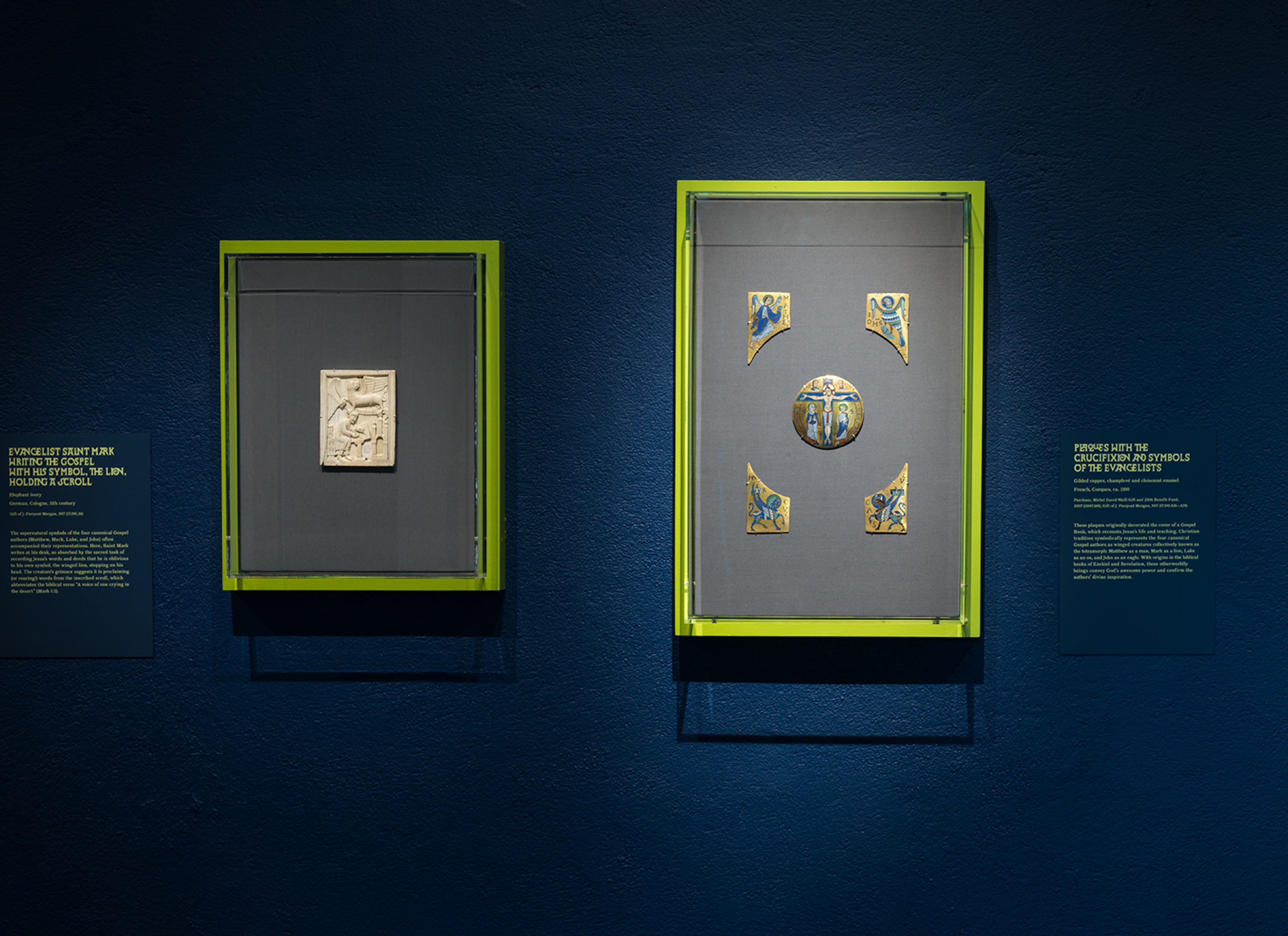 Two illuminated museum cases display historic Islamic artifacts—a carved ivory plaque and a decorated circular medallion with four corner pieces—against a deep blue wall