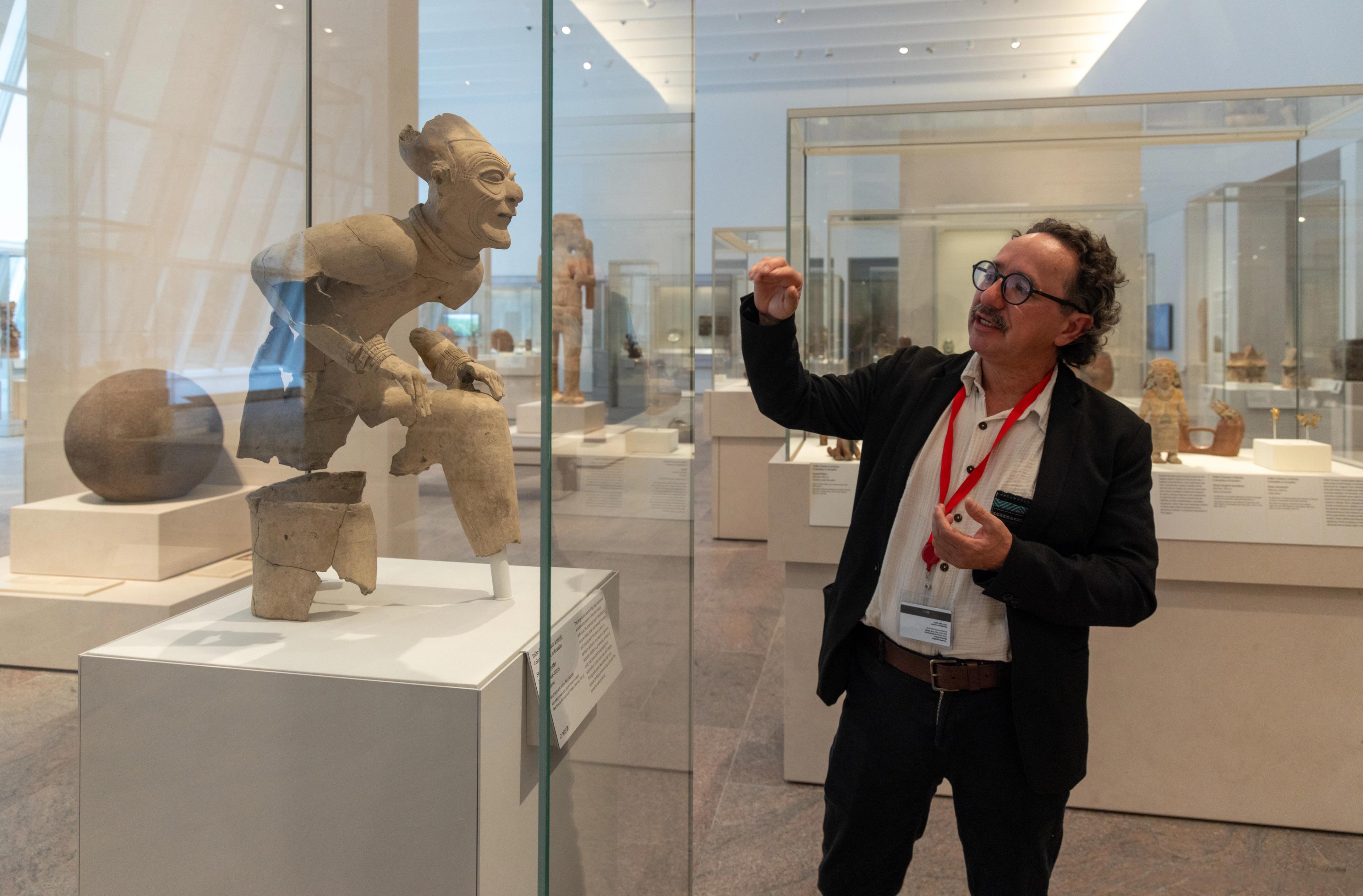 Florencio Delgado Espinoza gestures to the seated elder statue in the Arts of the Ancient Americas galleries.