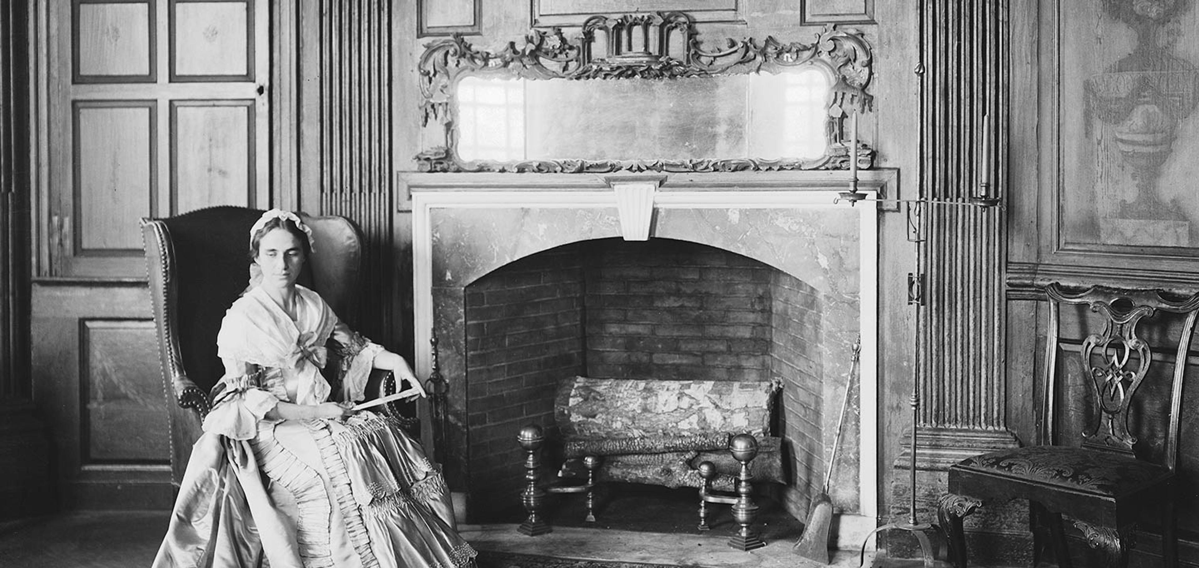 Black-and-white image of an actor in 18th-century period costume sitting in the Marmion Room