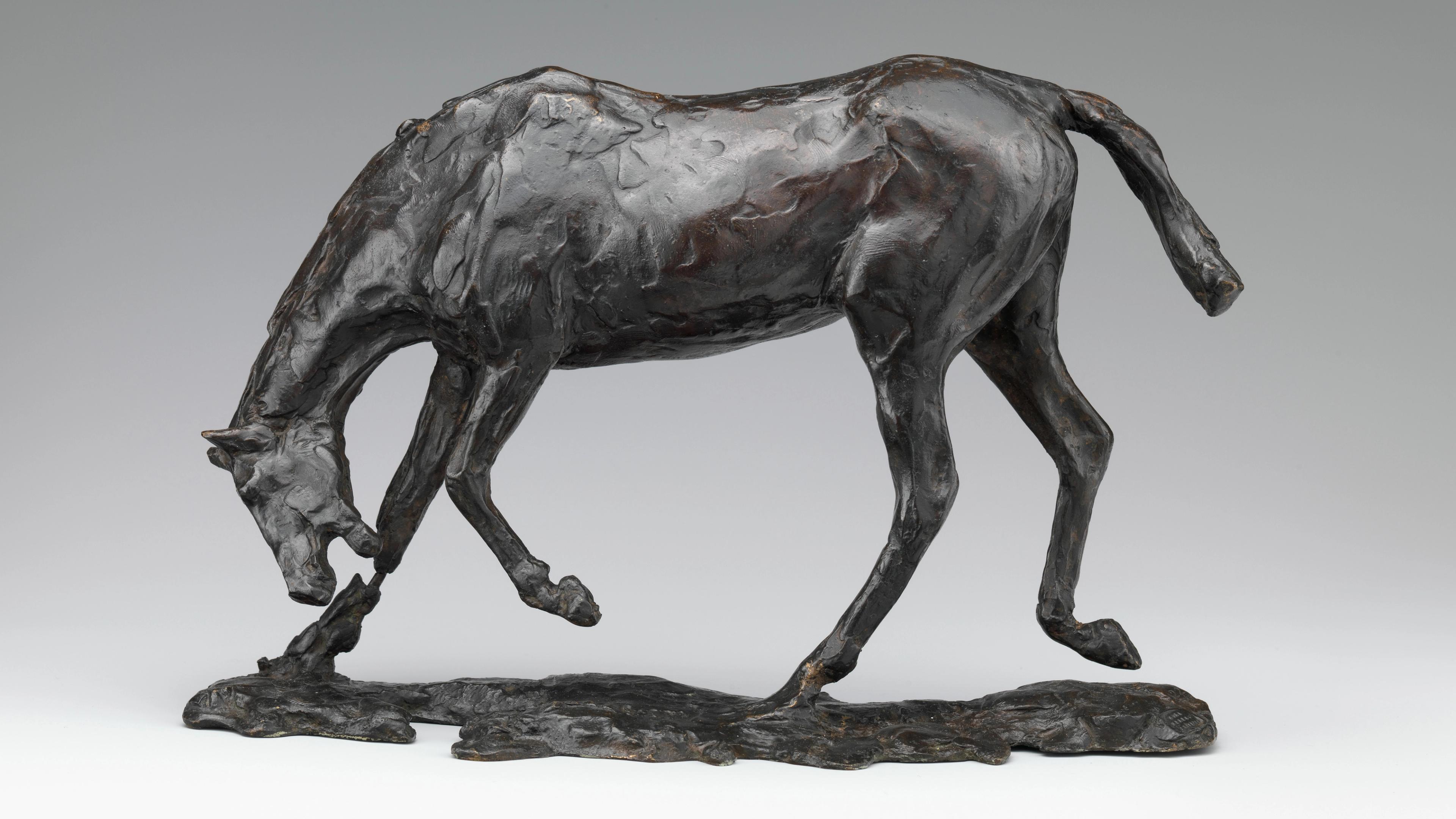 Brown-black sculpture of a horse in motion, its head angled towards the ground and mouth open.